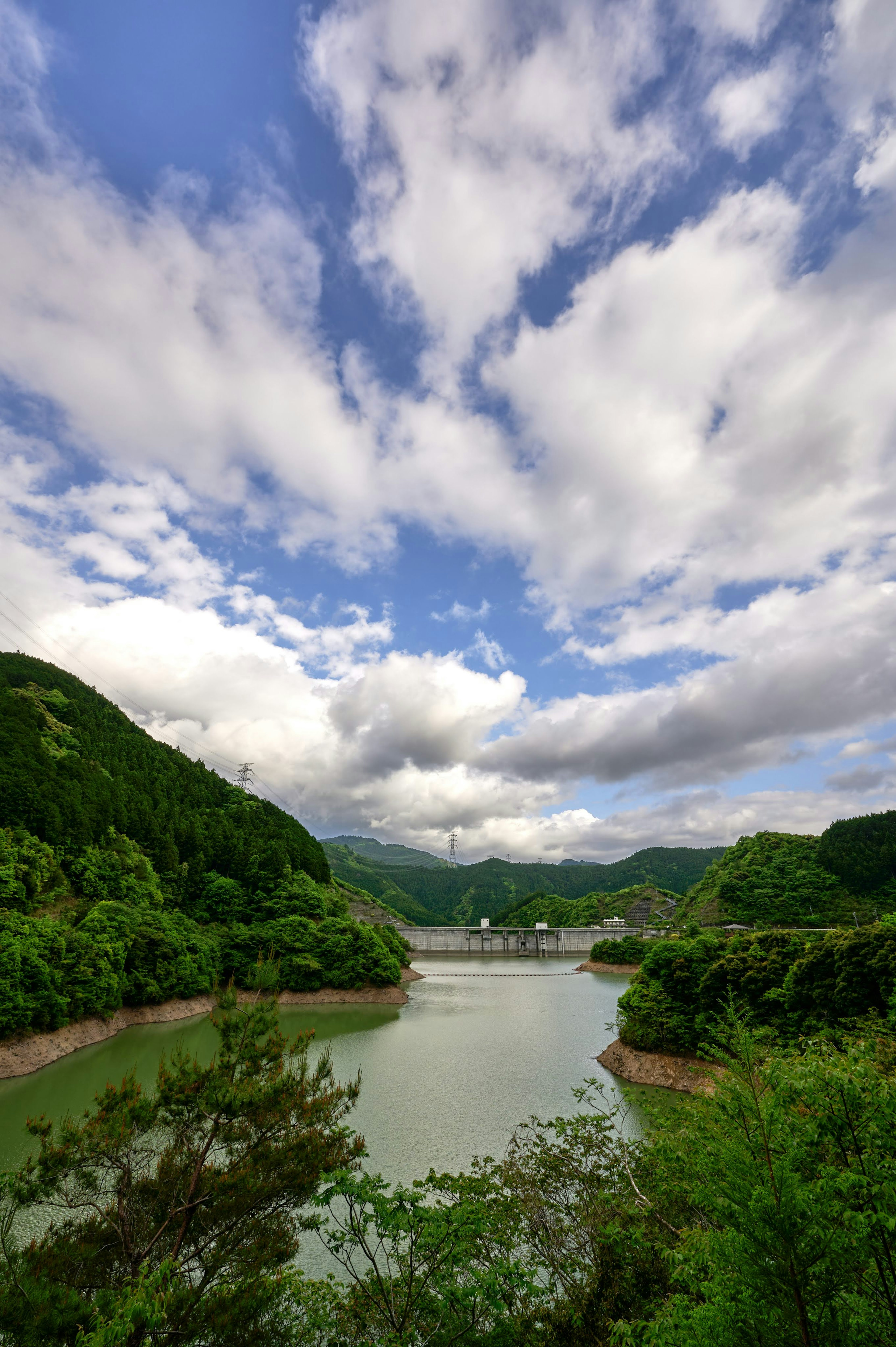 Calm lake surrounded by lush mountains and blue sky