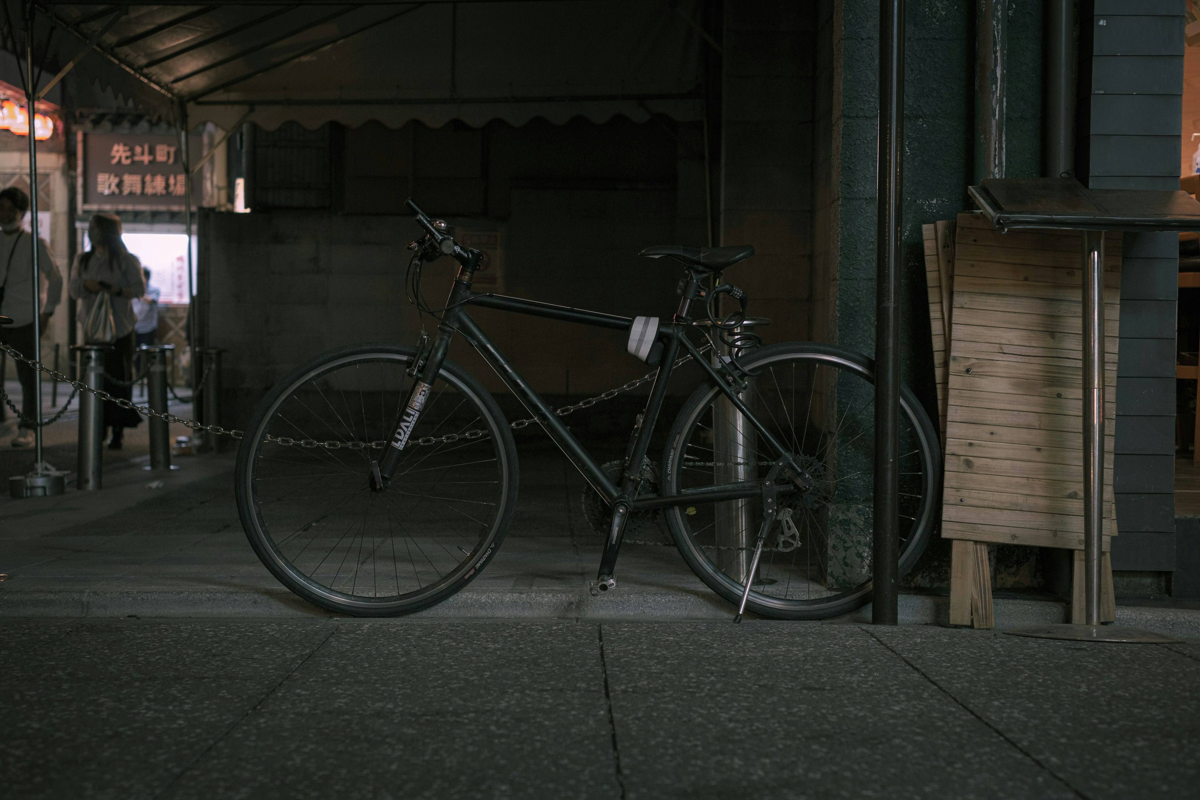 Ein altes Fahrrad lehnt an einer Wand in einer schwach beleuchteten Gasse