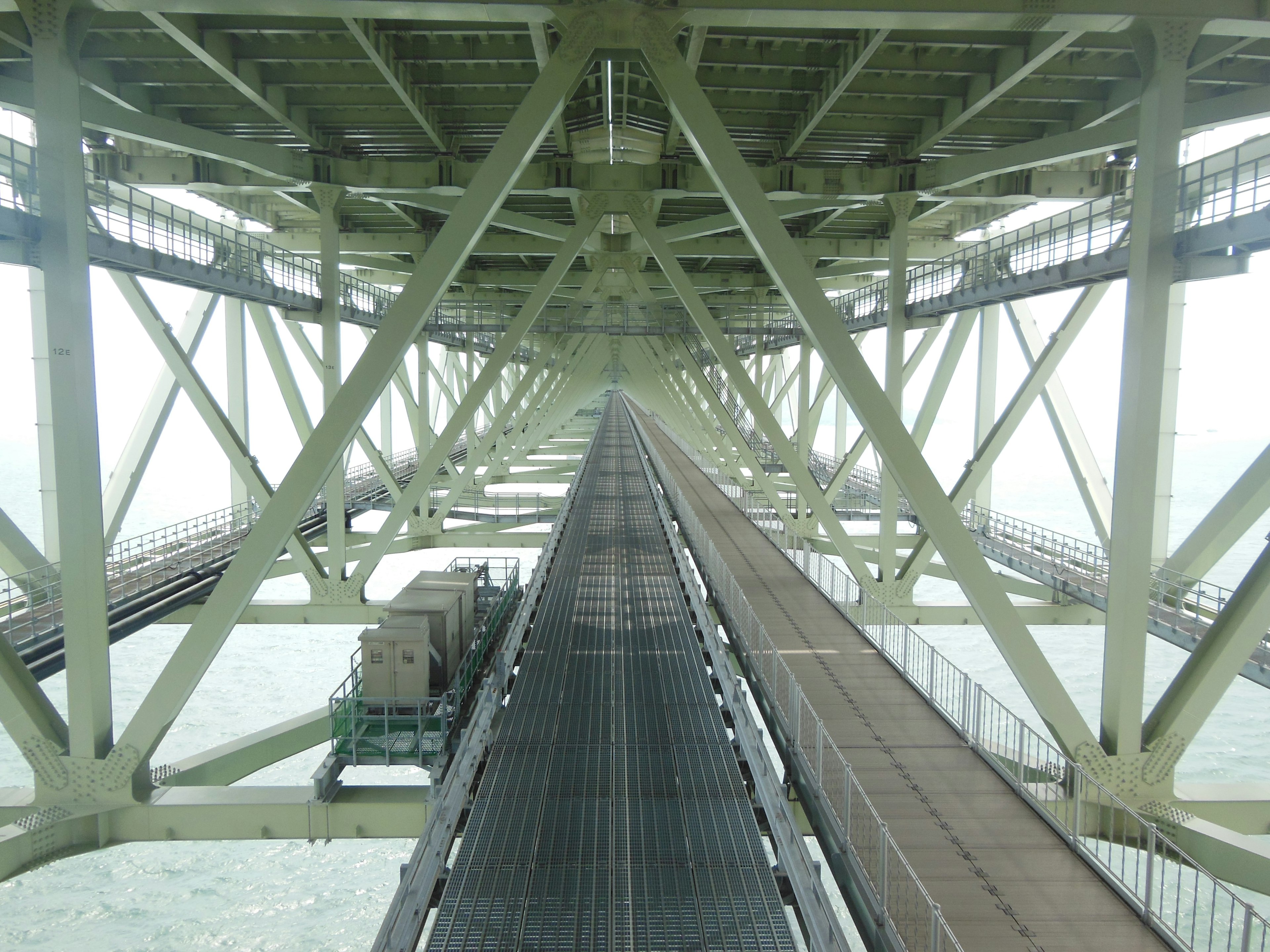 Vue de dessous d'un pont montrant des éléments structurels et des voies ferrées s'étendant au loin