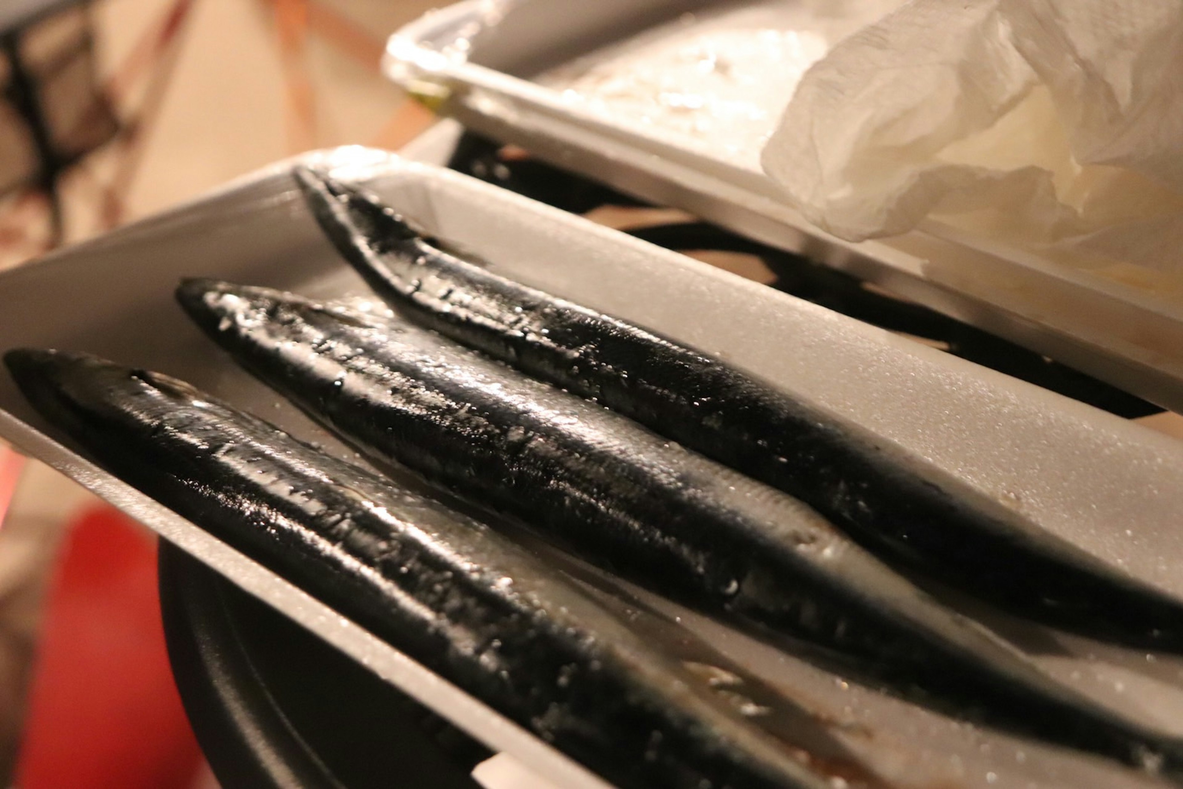 Close-up of black eel fish arranged on a white tray