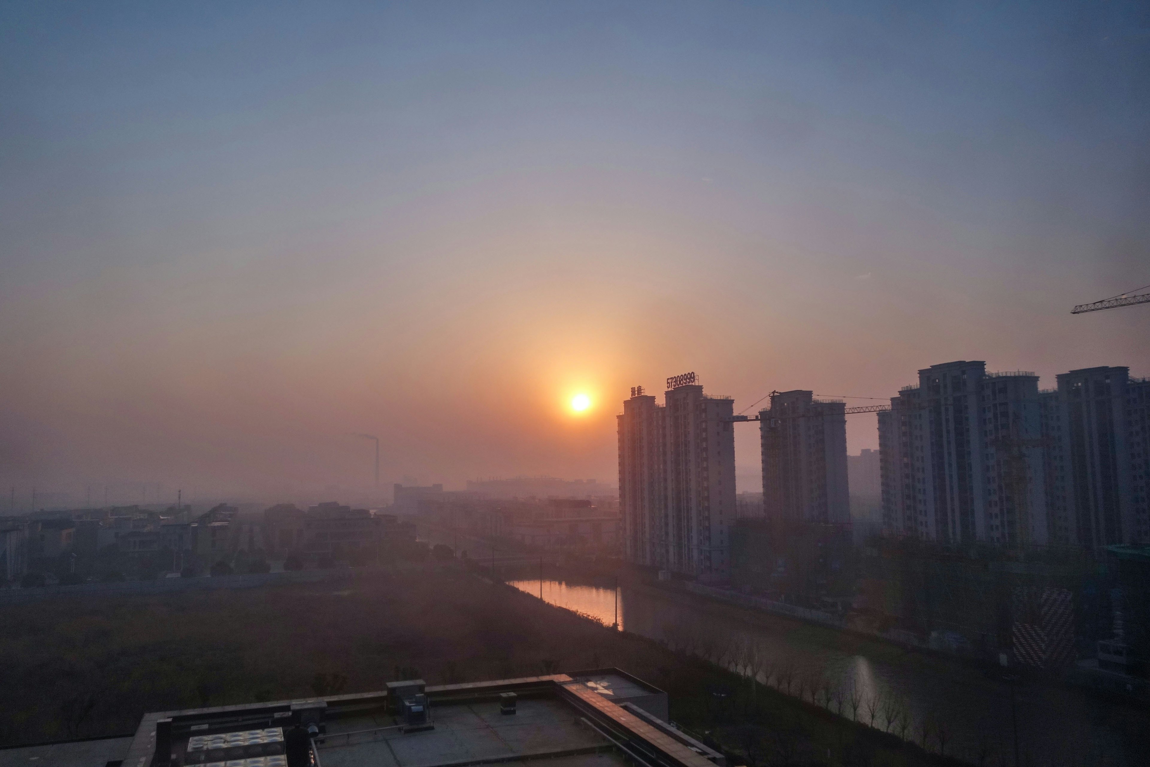 Stadtlandschaft bei Sonnenaufgang mit Wolkenkratzern und ruhigem Wasser