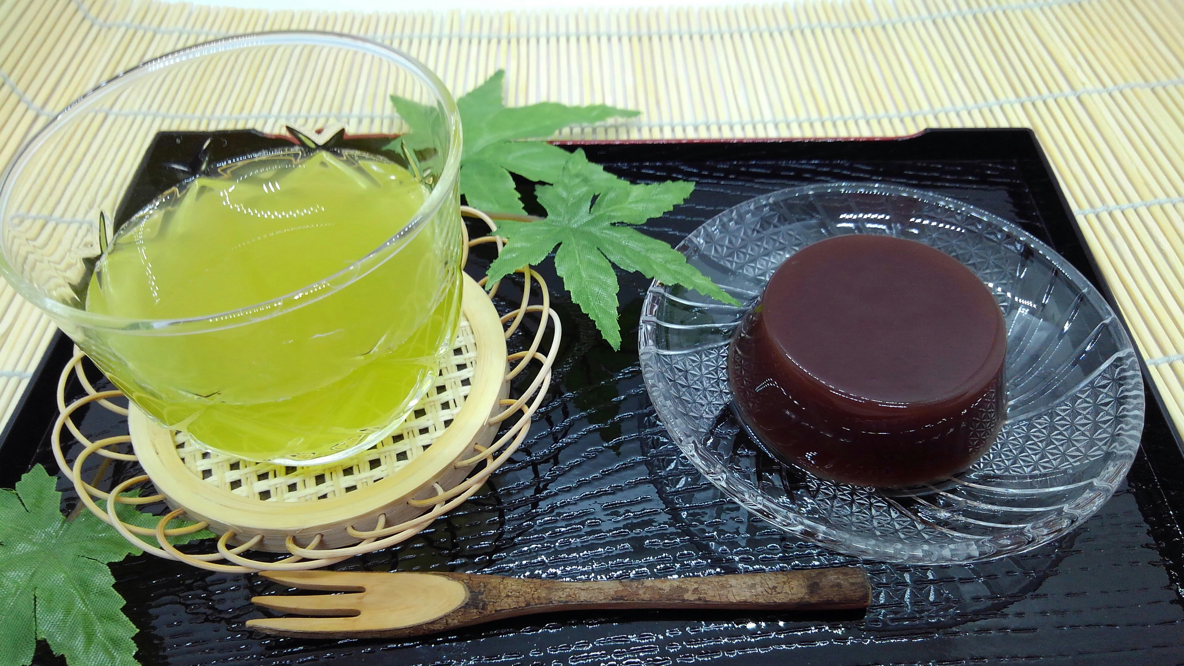 Una foto de té verde y dulces japoneses tradicionales en una bandeja negra