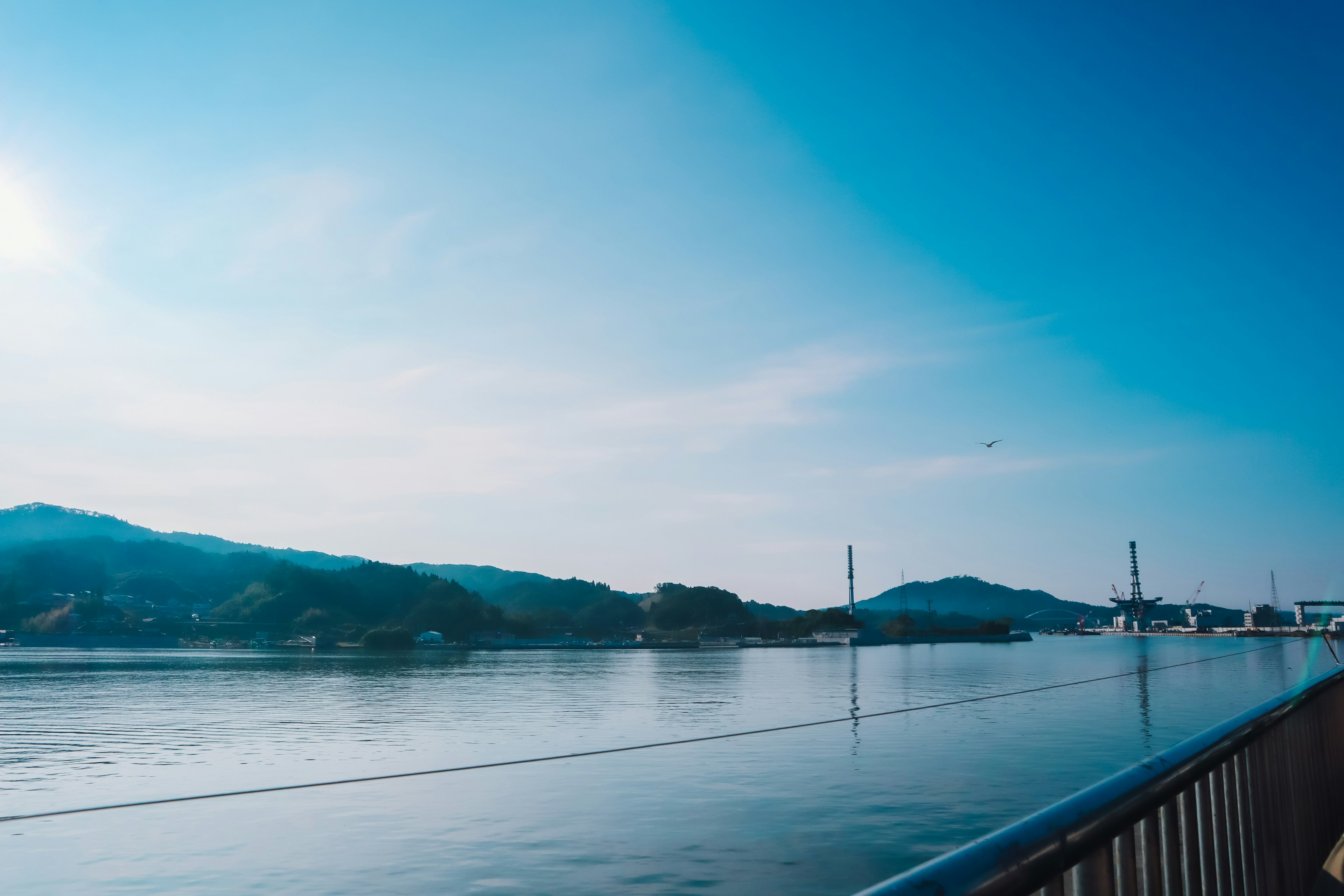 宁静的河流在蓝天之下的风景，远处有山丘和一座桥