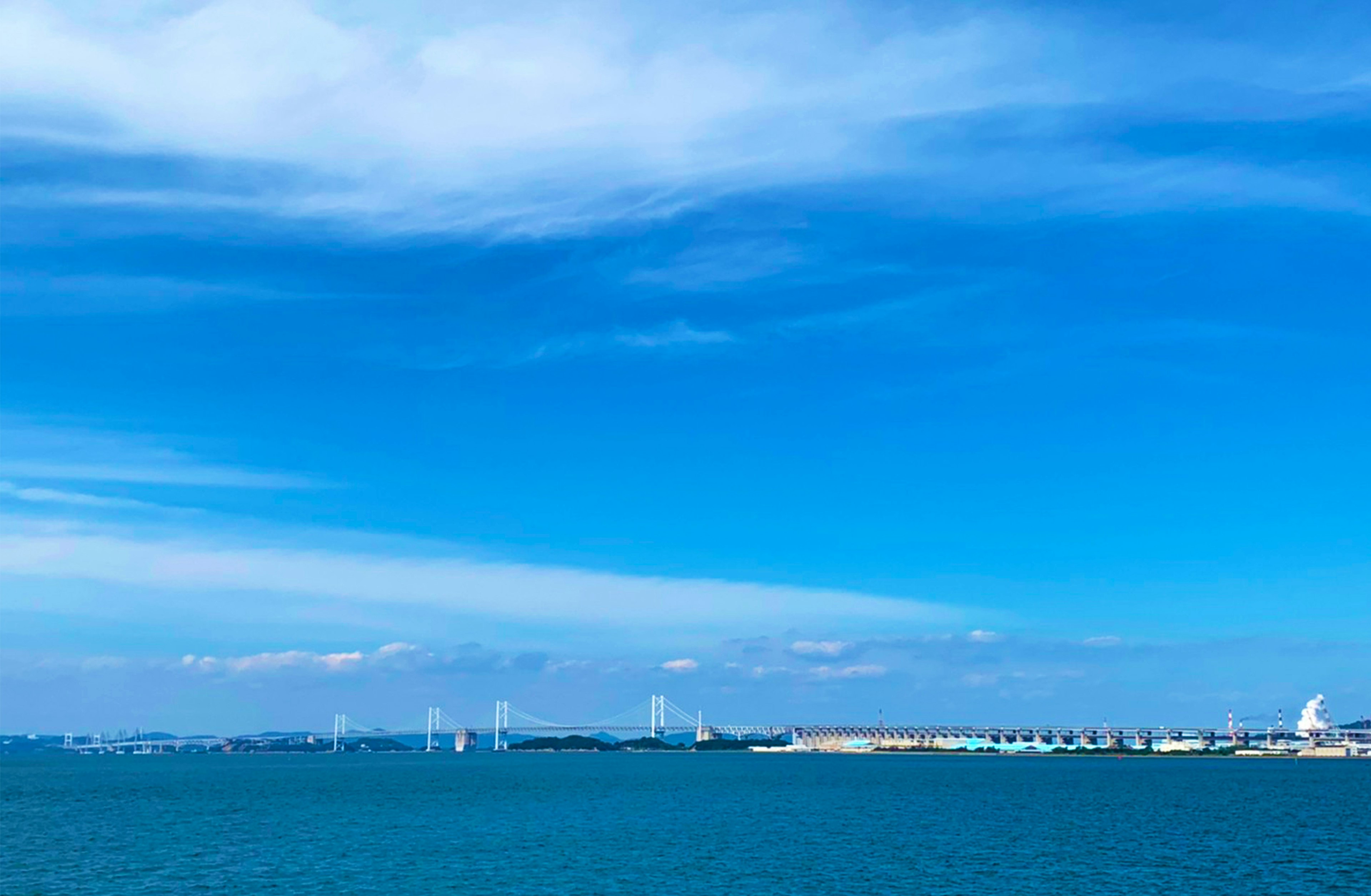 Eine Panoramaansicht von blauem Meer und Himmel mit einem Hafen in der Ferne