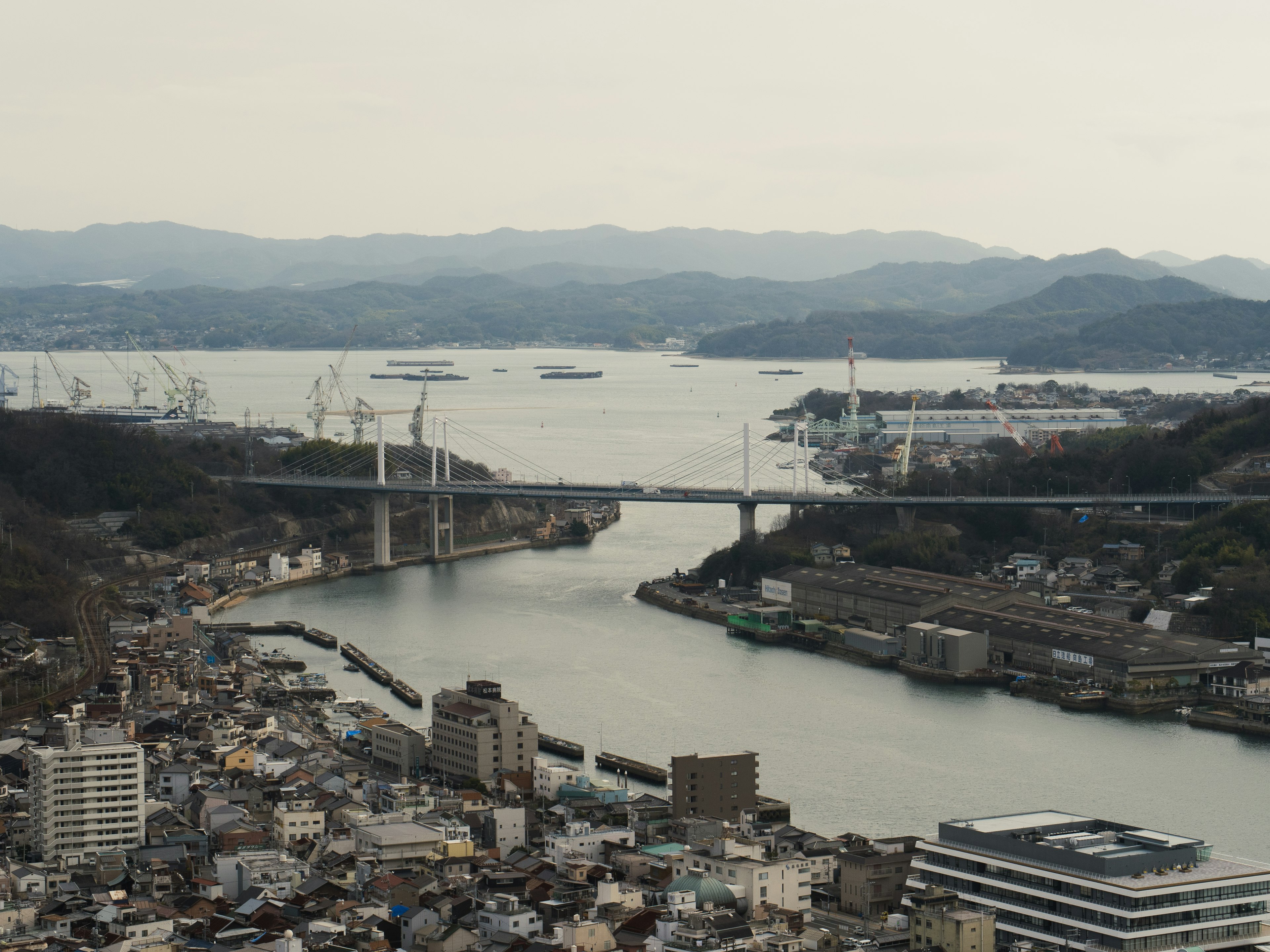 ทิวทัศน์เมืองที่มีทะเลและภูเขาเป็นฉากหลัง สะพานข้ามแม่น้ำ เรือจอดเทียบท่า