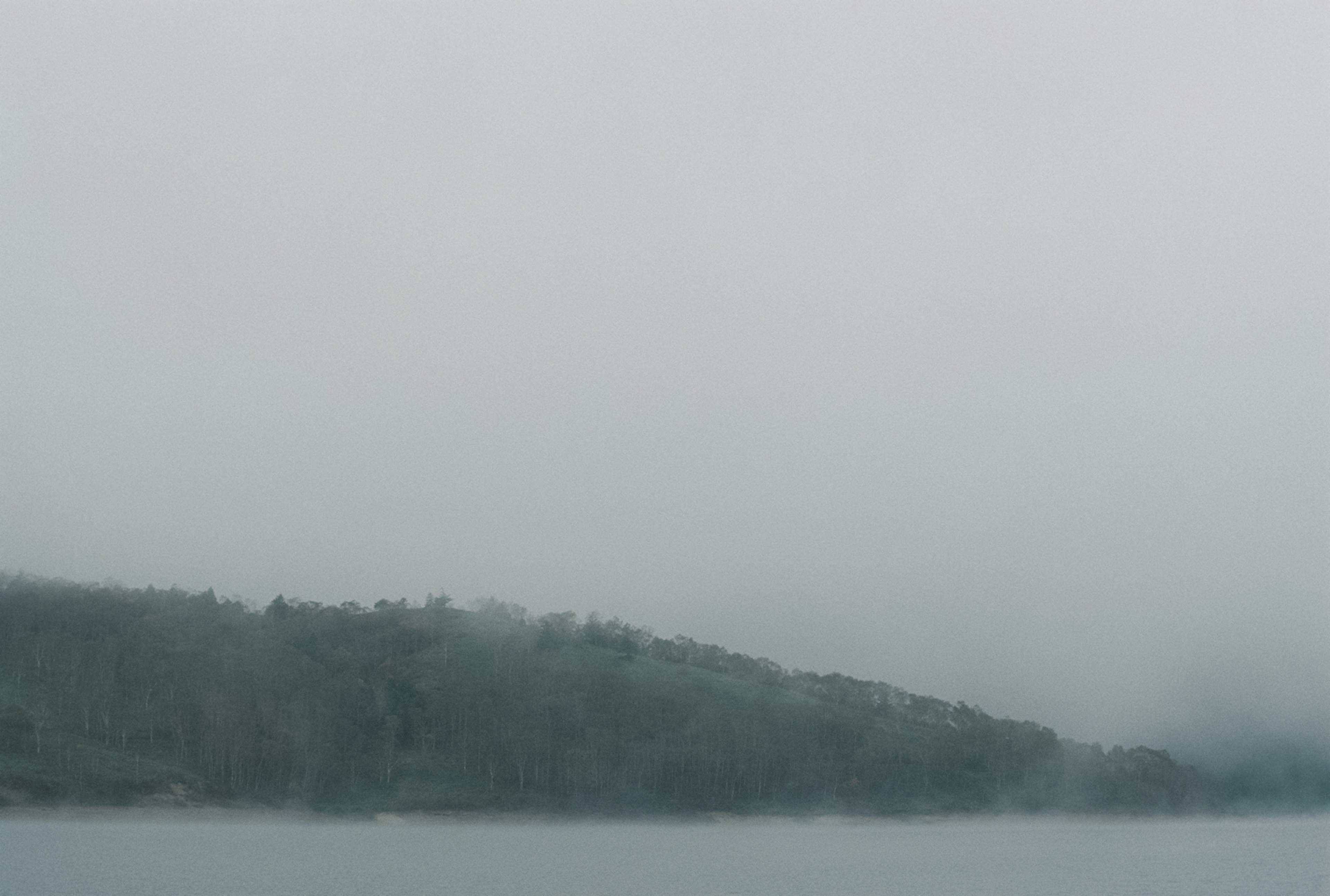 Escena de lago neblinoso con colinas verdes