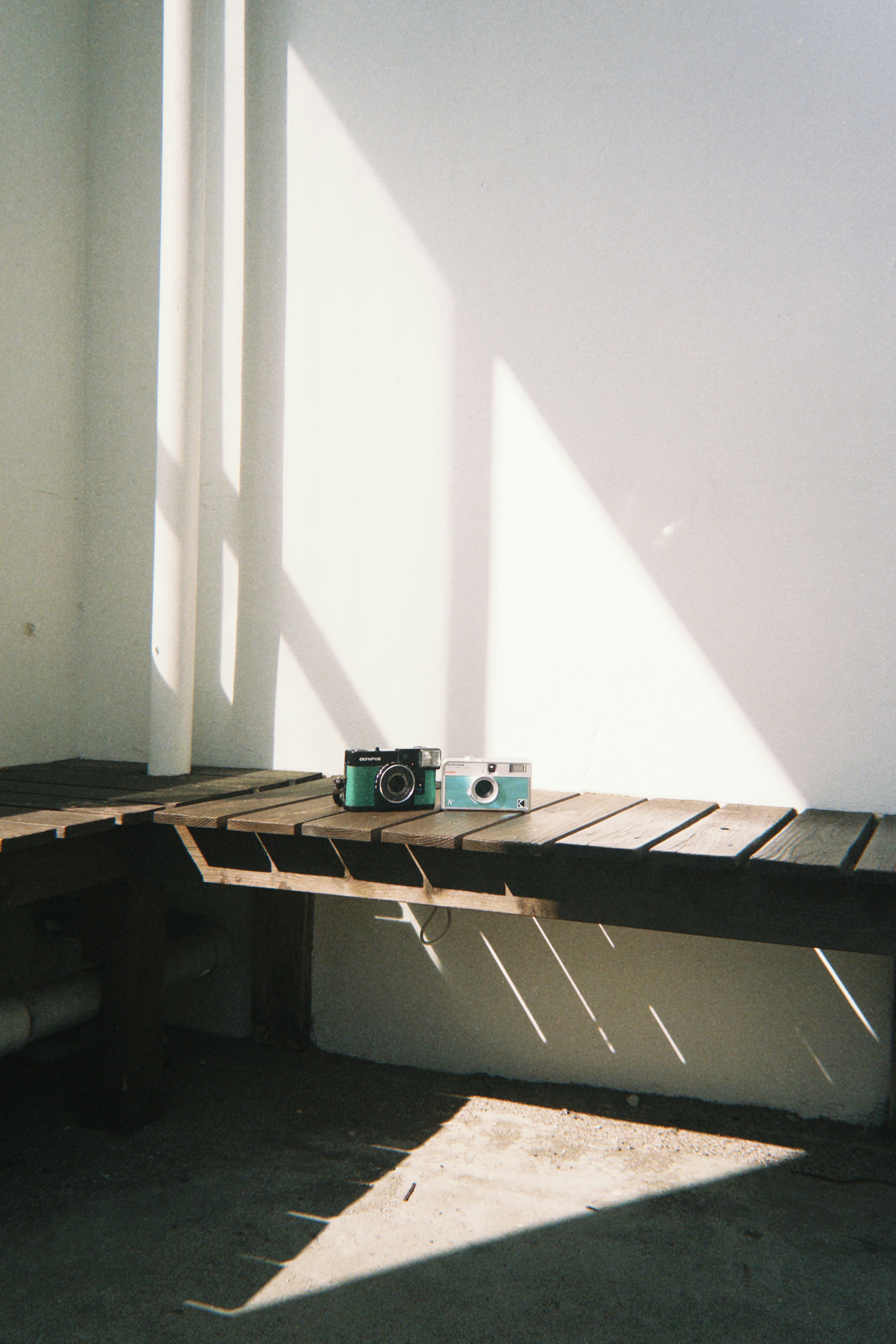 A quiet corner of a room with cameras placed on a wooden bench