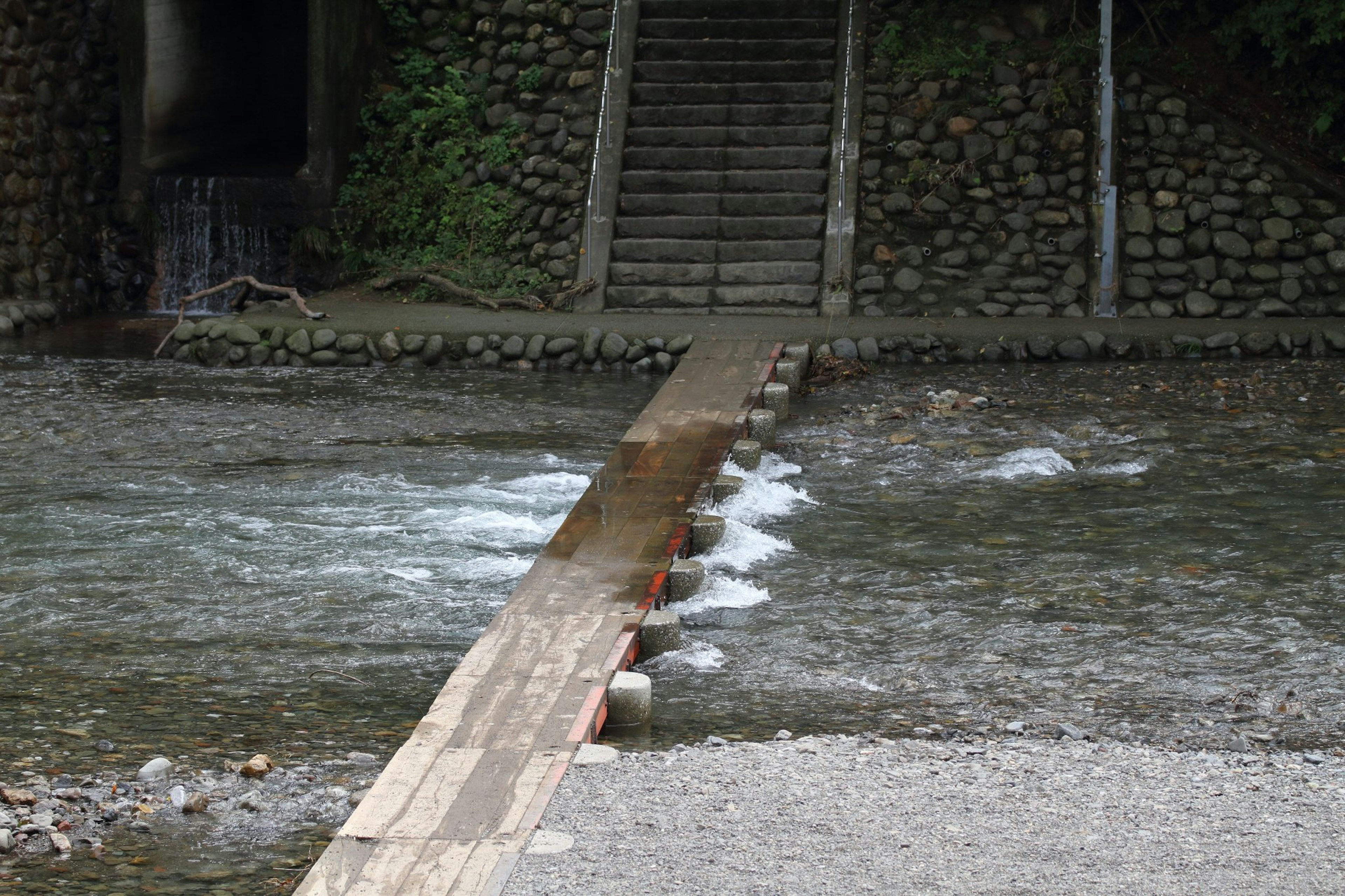 Puente de madera sobre un río con escaleras de piedra