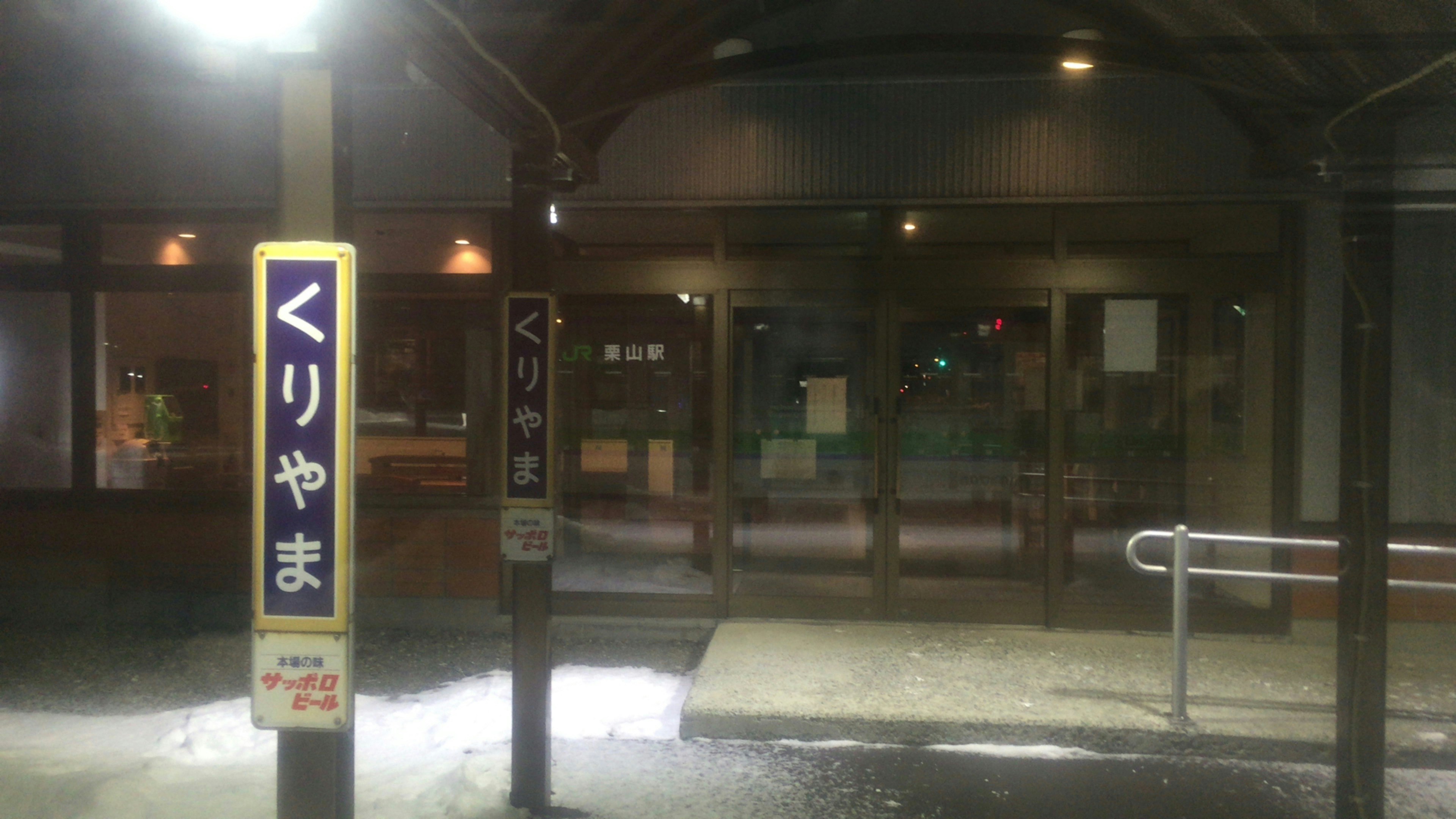 Entrada de la estación Kuri-yama iluminada bajo la lluvia