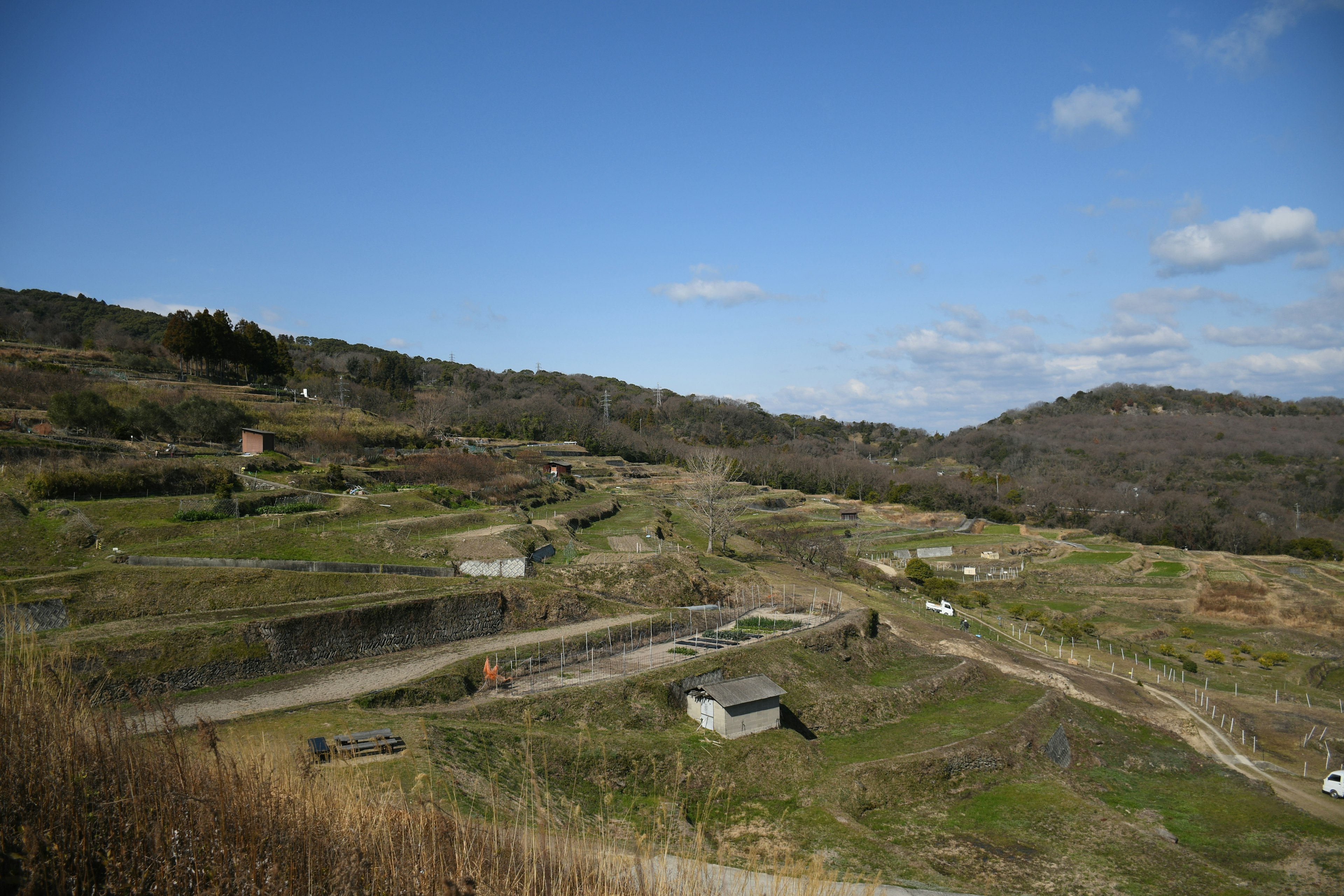 Paysage de terres agricoles et de petites cabanes entourées de collines verdoyantes