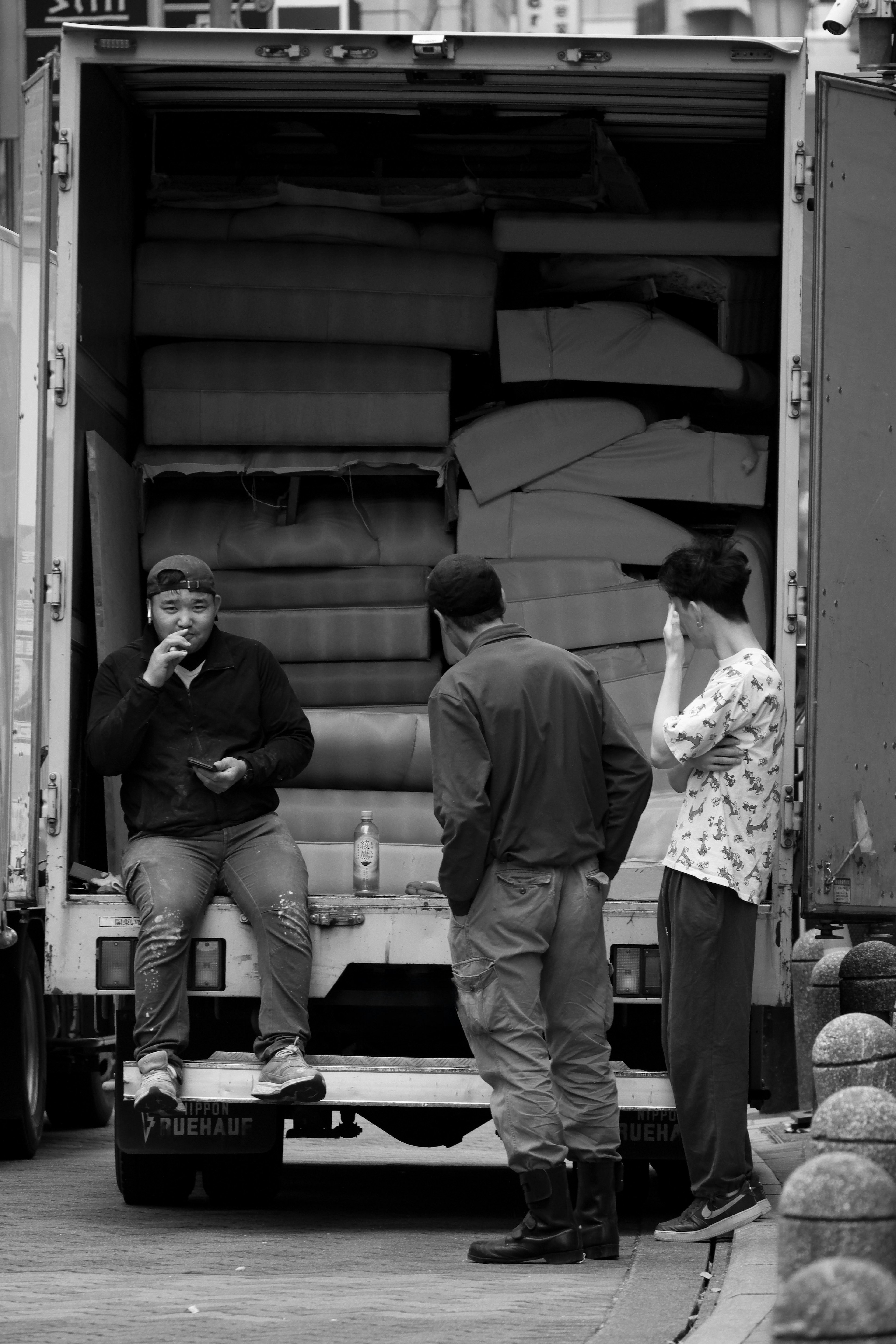 Three men talking in front of a truck loaded with mattresses