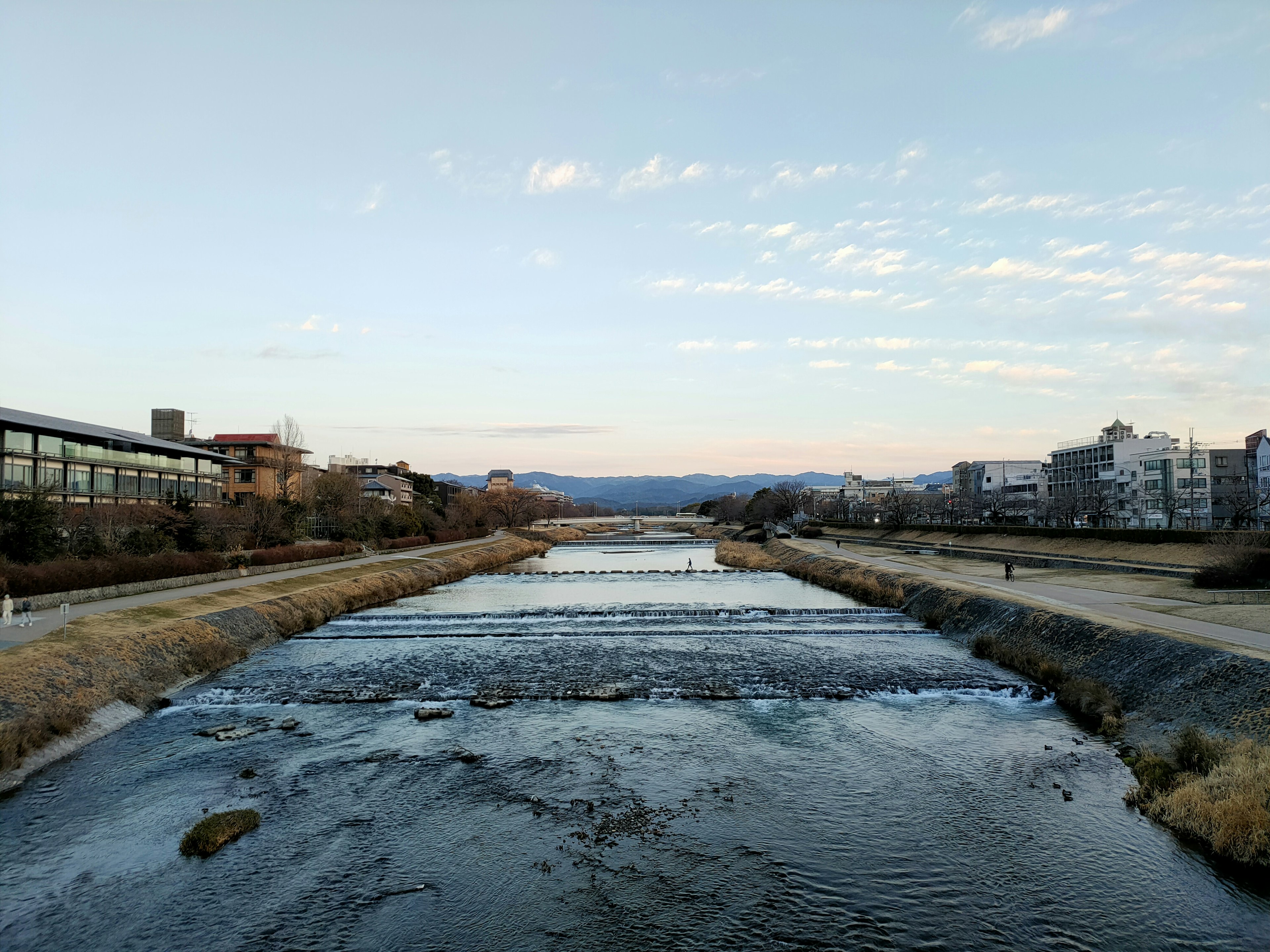 Serene river landscape with buildings under a blue sky