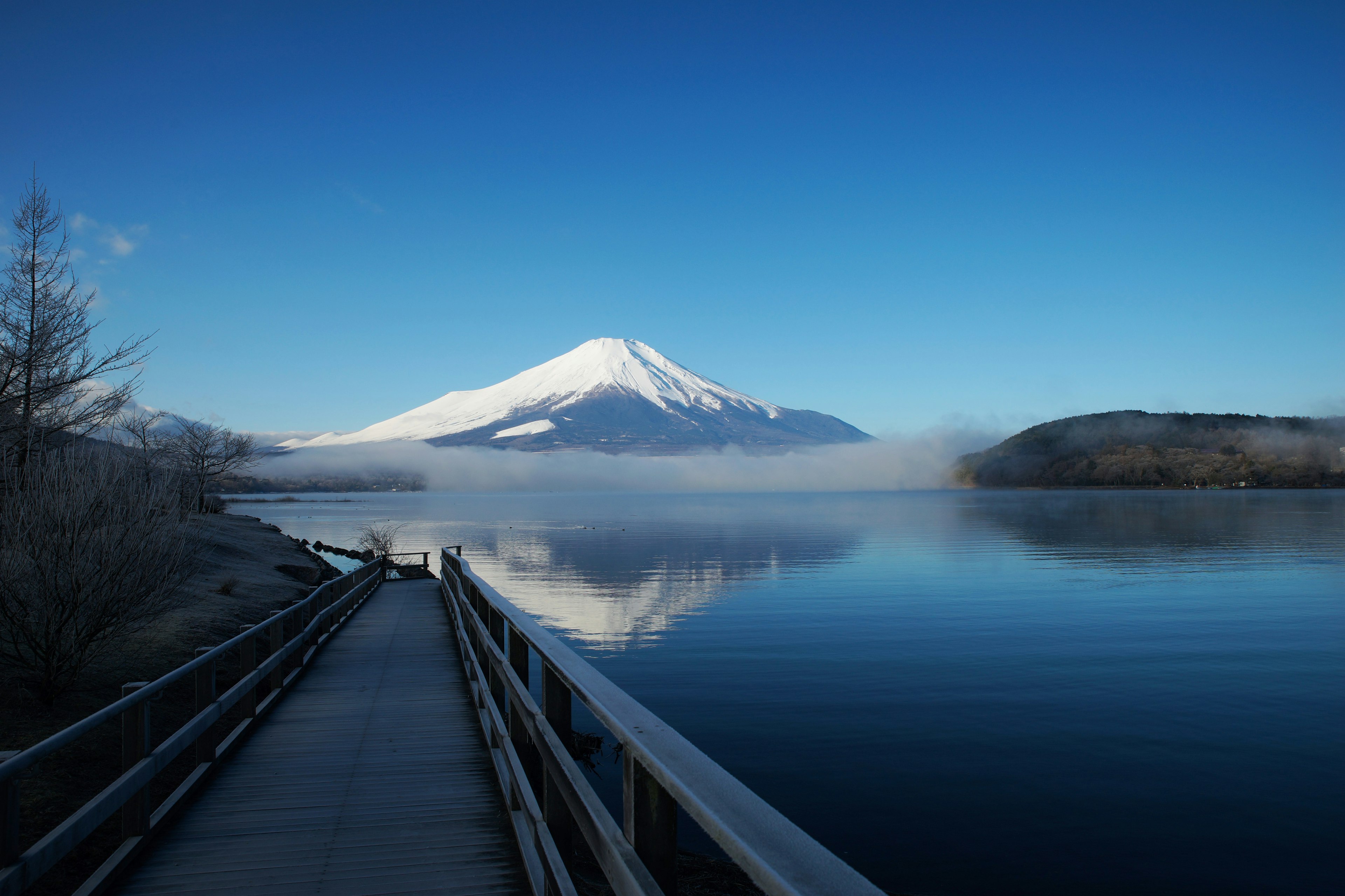 ทิวทัศน์ที่สวยงามของภูเขาฟูจิพร้อมทะเลสาบสงบและท้องฟ้าสีฟ้า