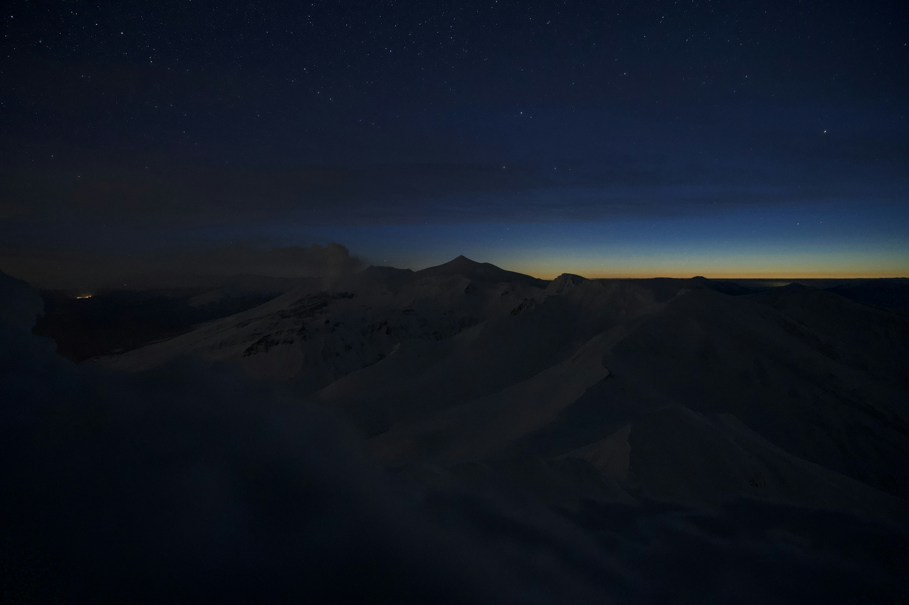 Bergsilhouette unter einem sternenklaren Nachthimmel mit schwachem Horizont