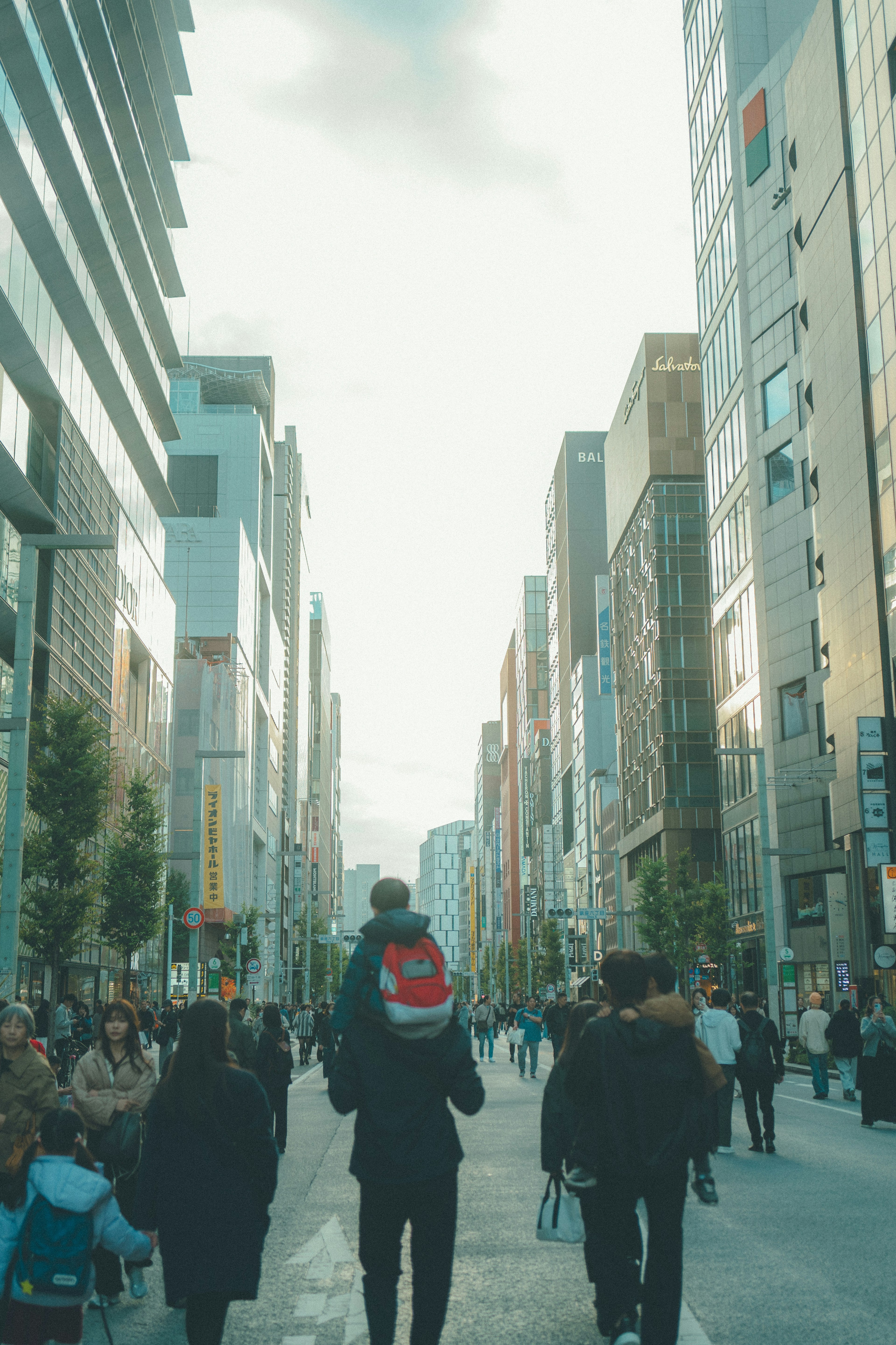 Father carrying child on shoulders walking through busy street