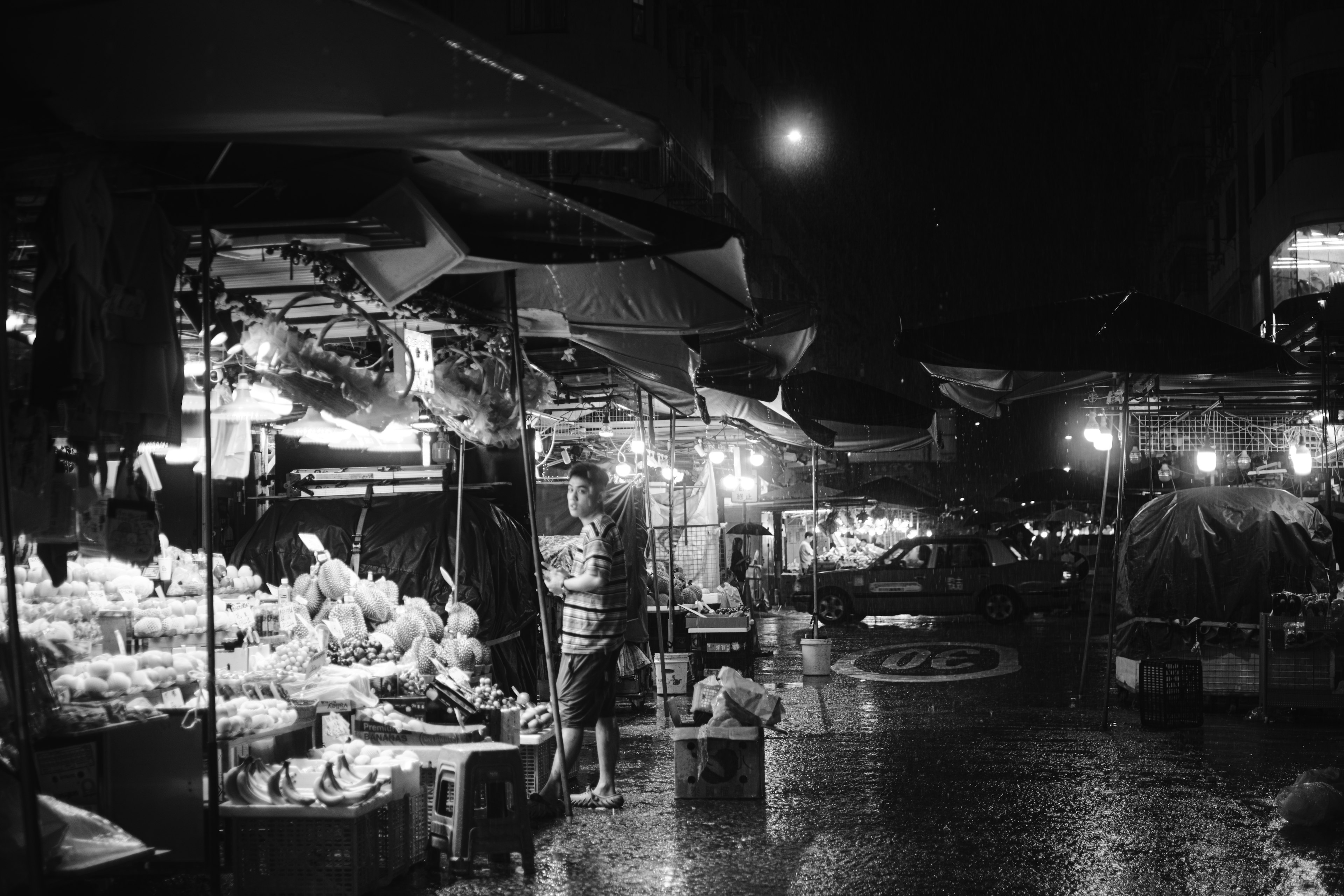 Pemandangan pasar malam dengan kios dan tampilan buah yang diterangi