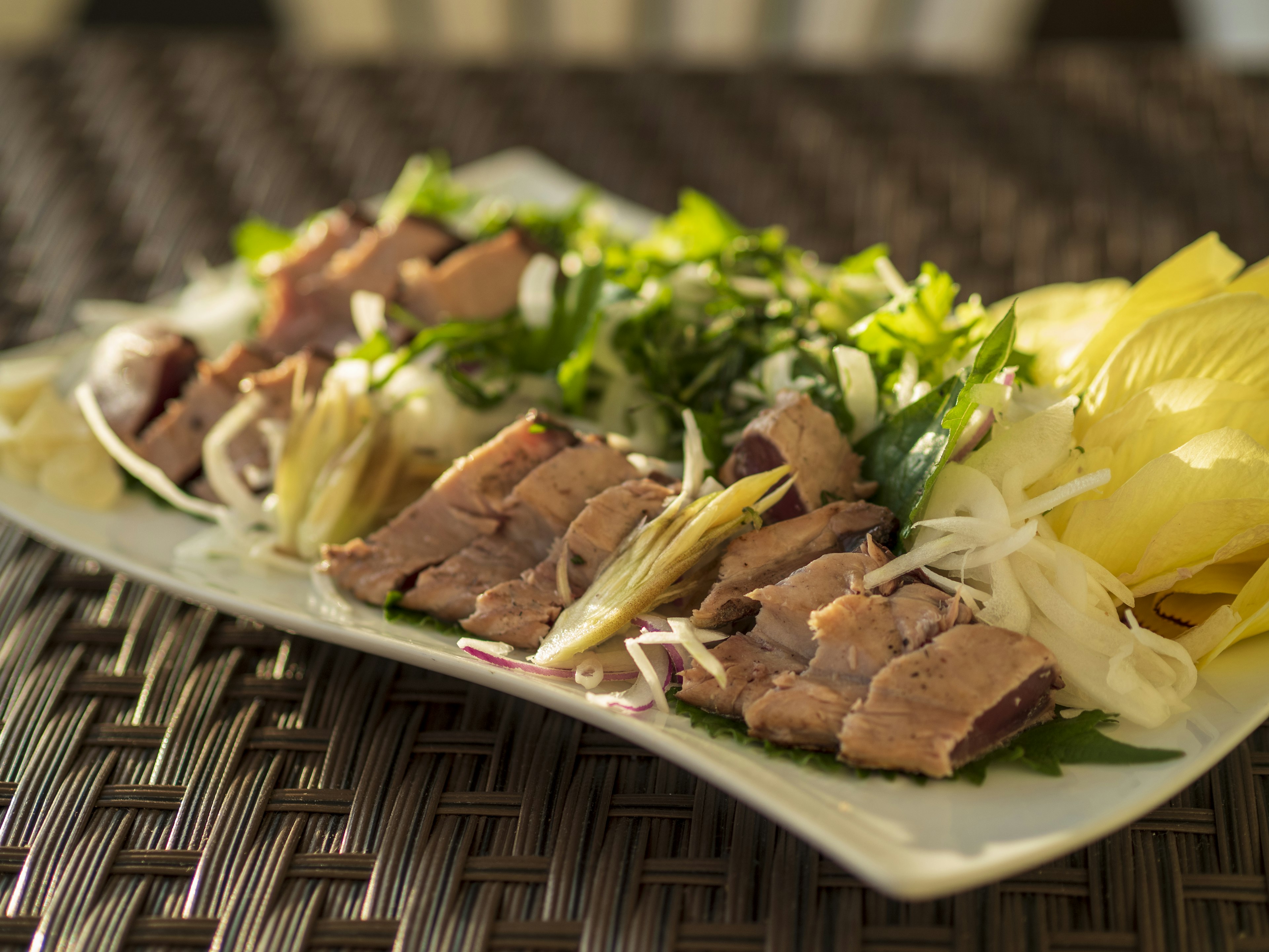 Platter of sliced meat garnished with fresh herbs and vegetables