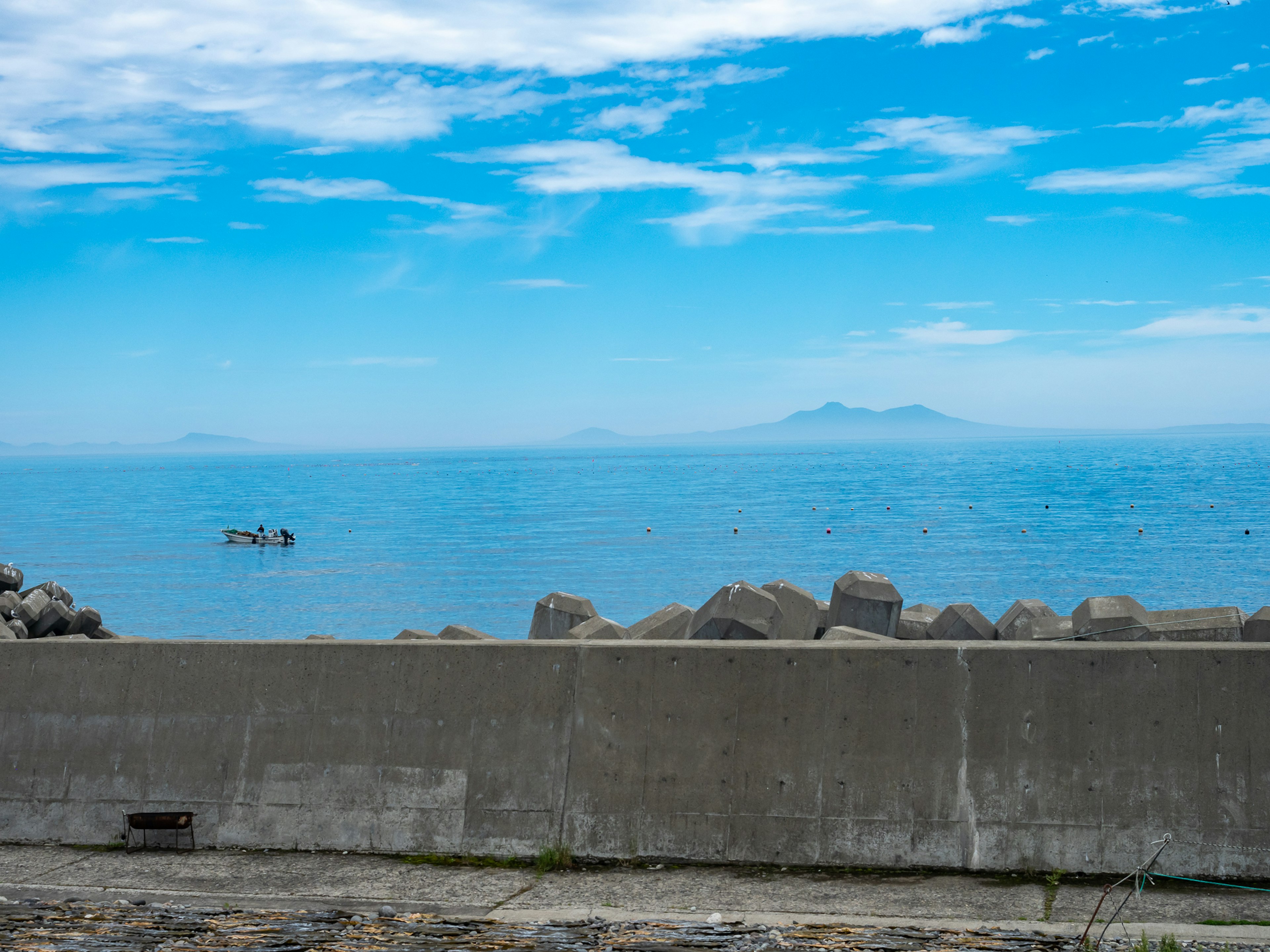 Vista escénica del océano azul y el cielo con un pequeño bote flotante