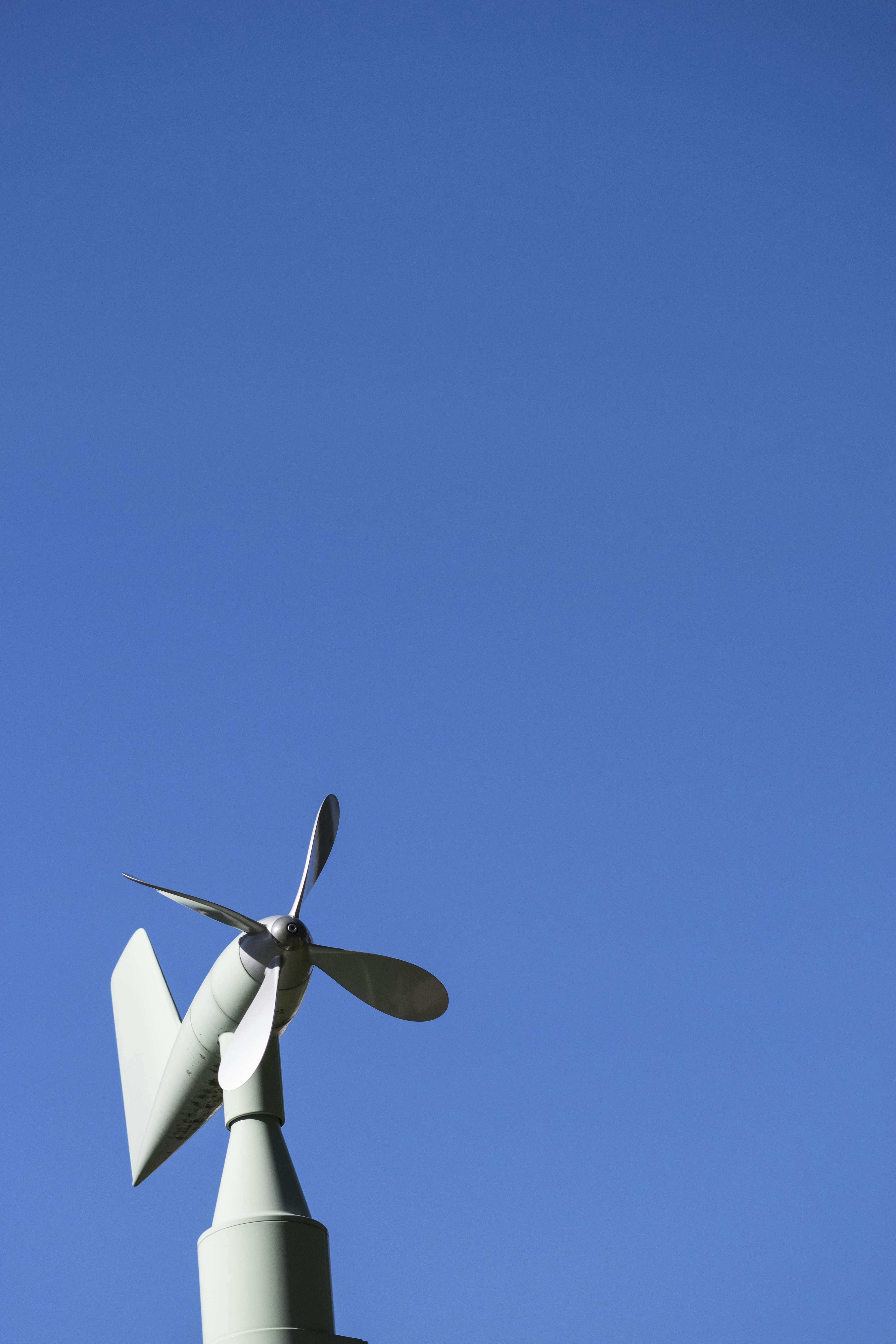 Blätter einer kleinen Windturbine vor einem klaren blauen Himmel