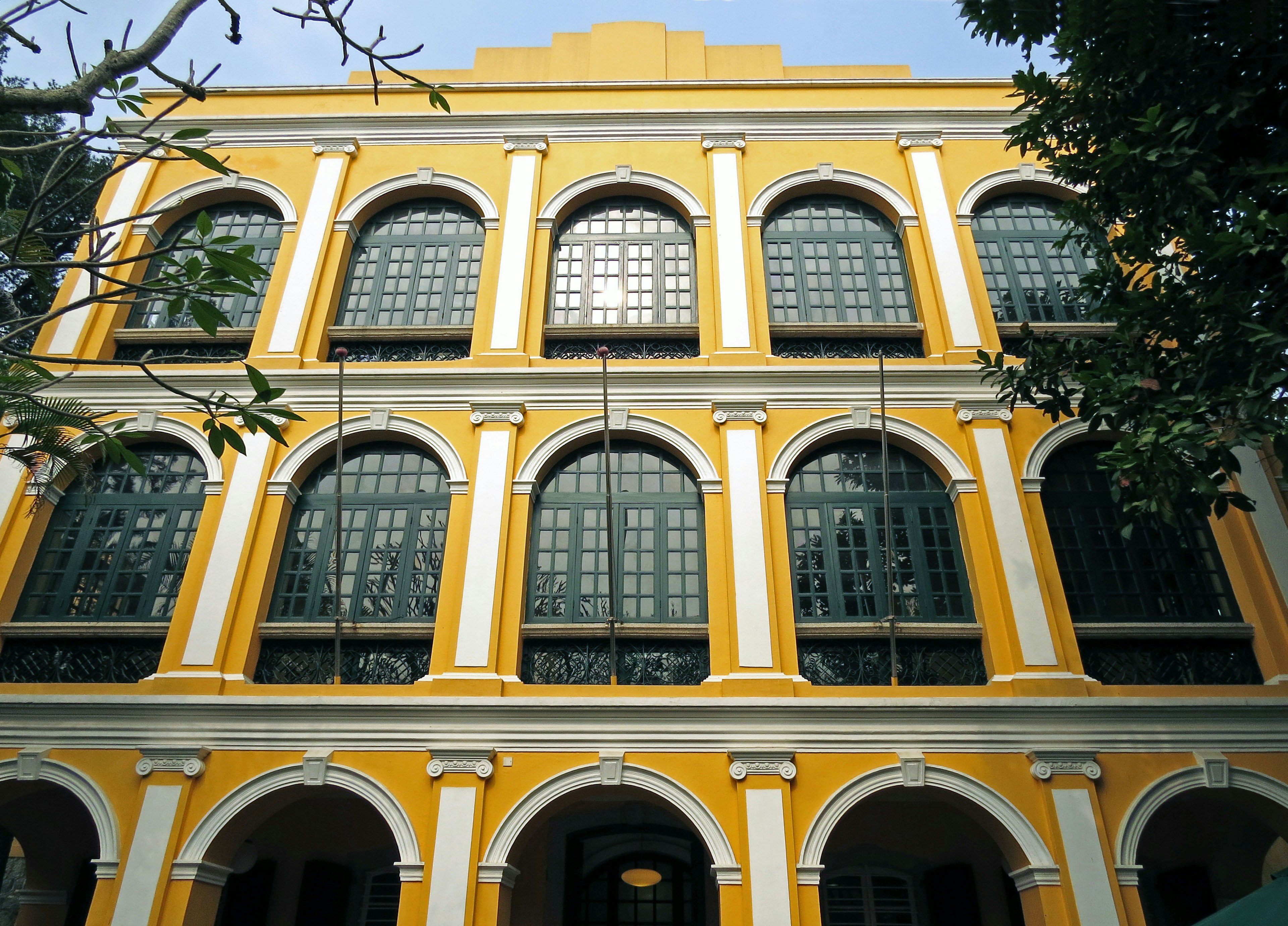 Bâtiment historique avec une façade jaune et de grandes fenêtres en arc