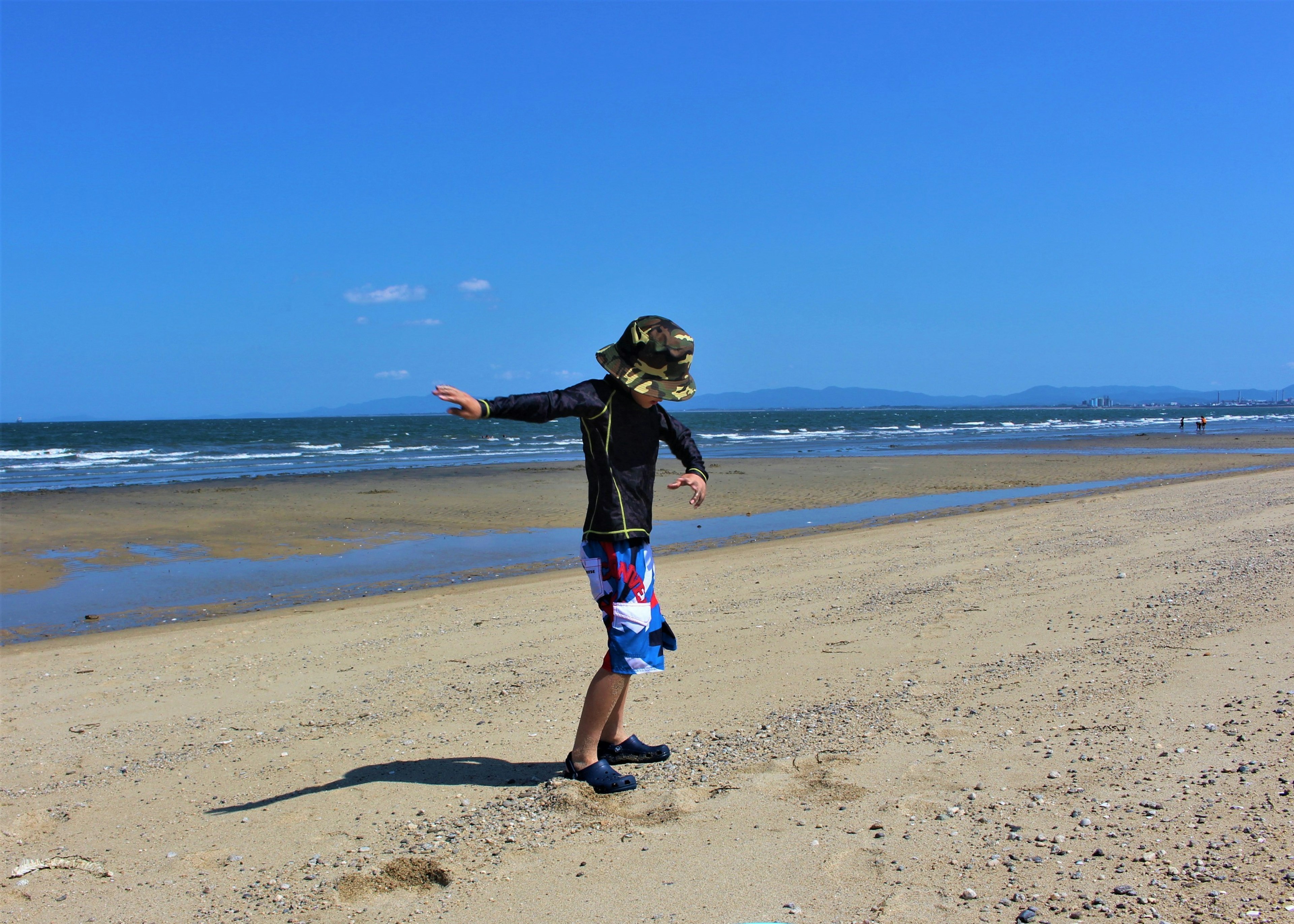 Ragazzo che gioca sulla spiaggia con cielo blu e onde dell'oceano