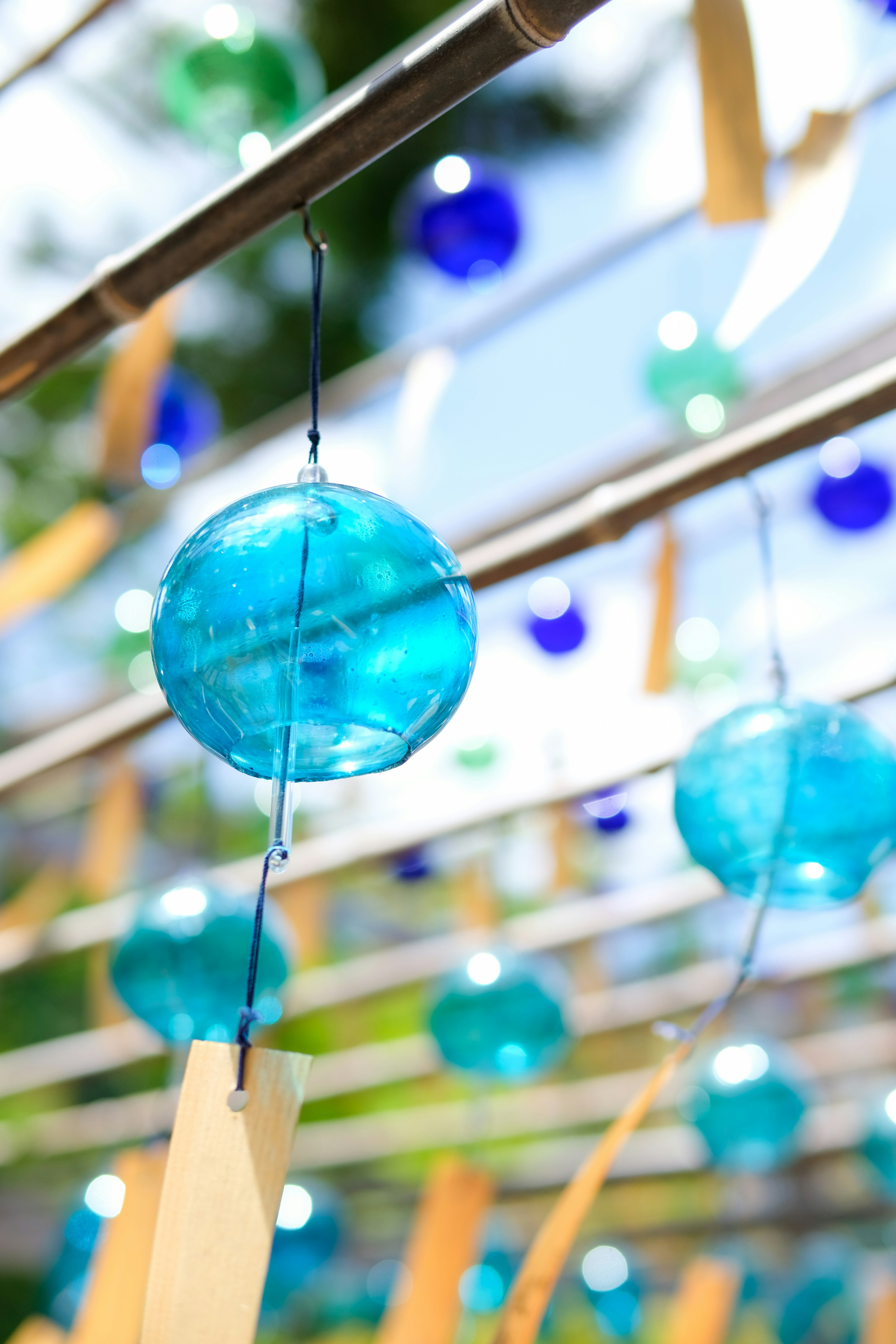 Blue wind chimes hanging in a vibrant outdoor setting