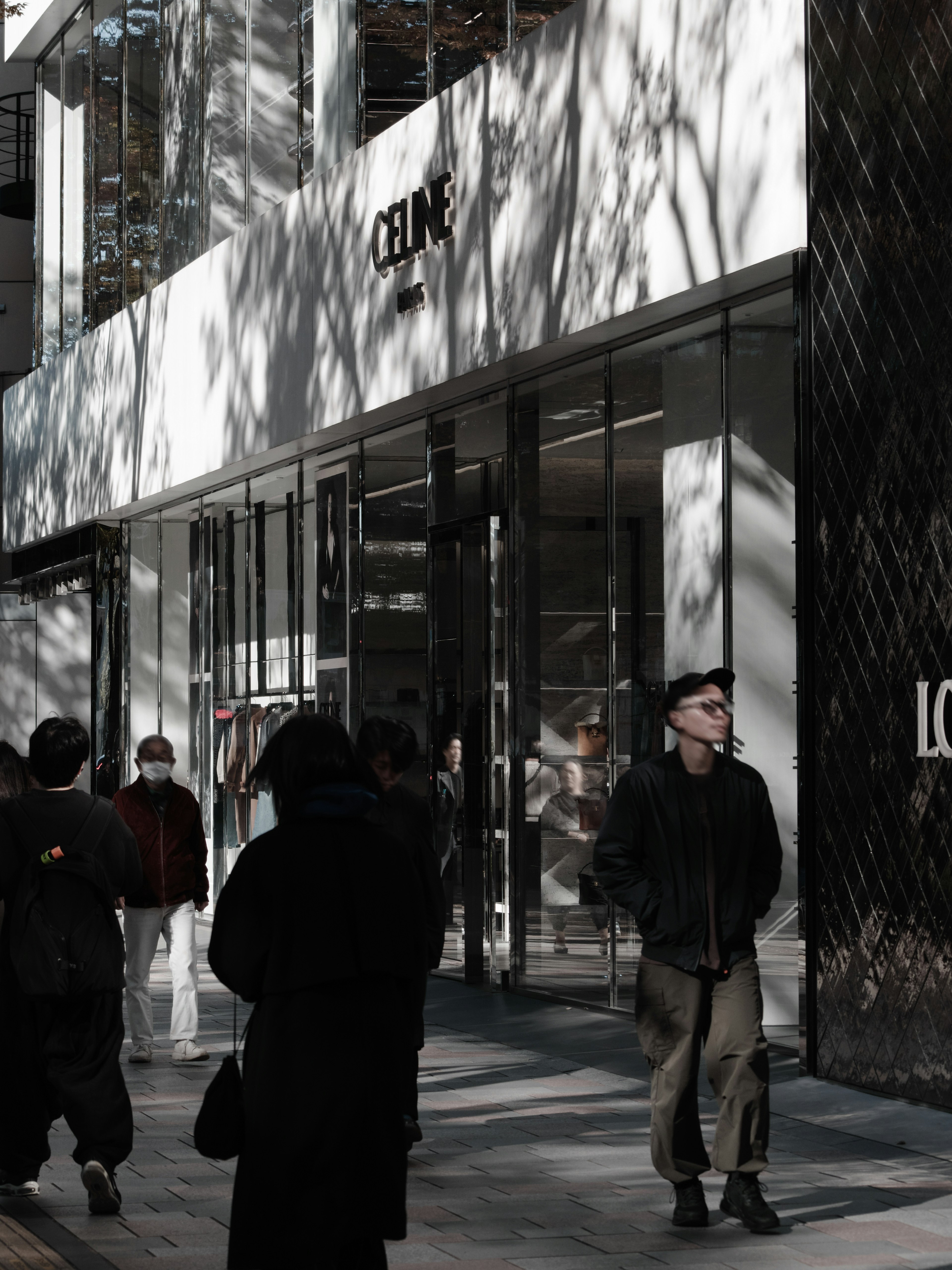 Personas de pie frente a una tienda Celine con sombras en la calle