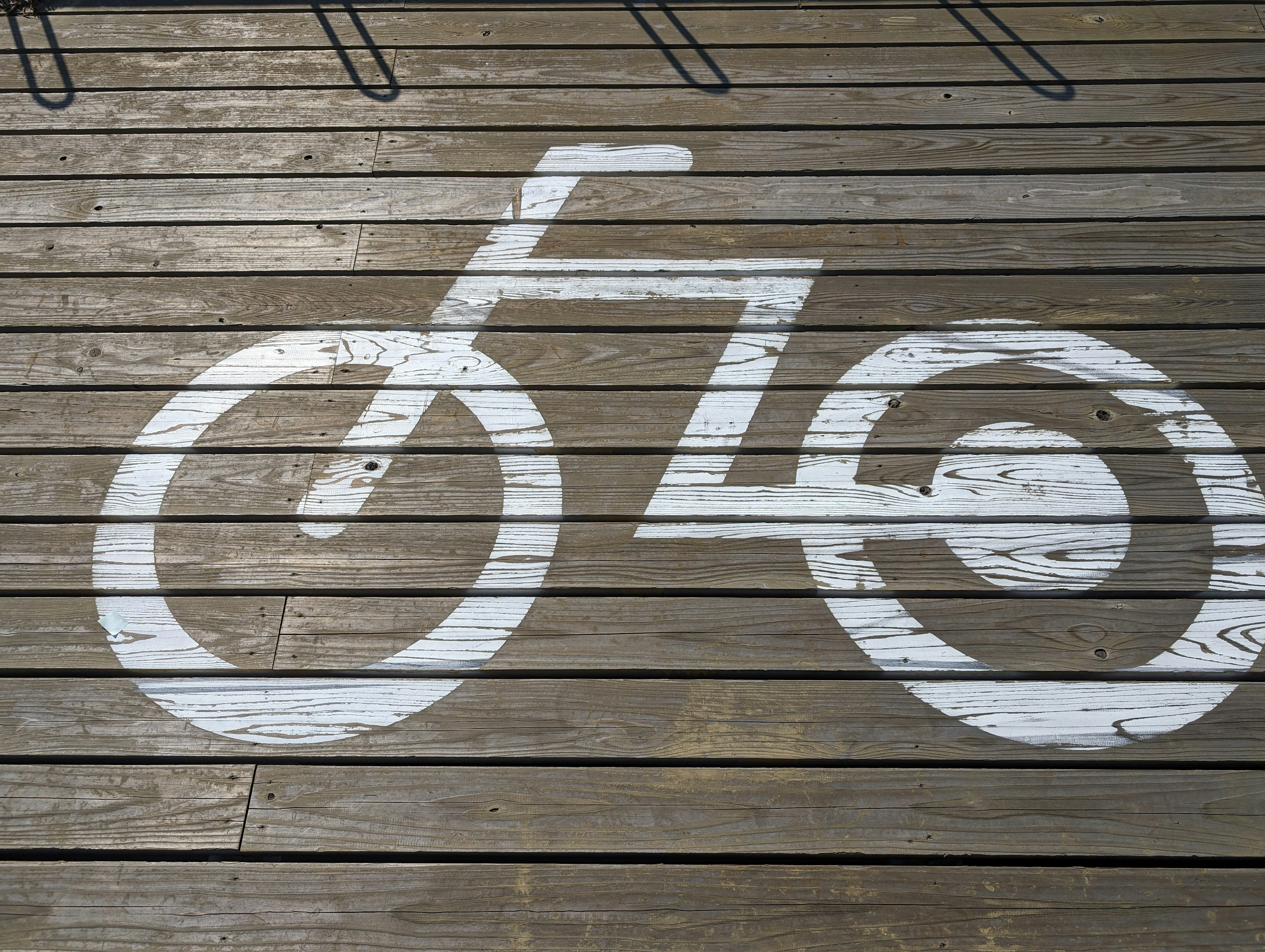 Icono de bicicleta blanca pintado en un suelo de madera