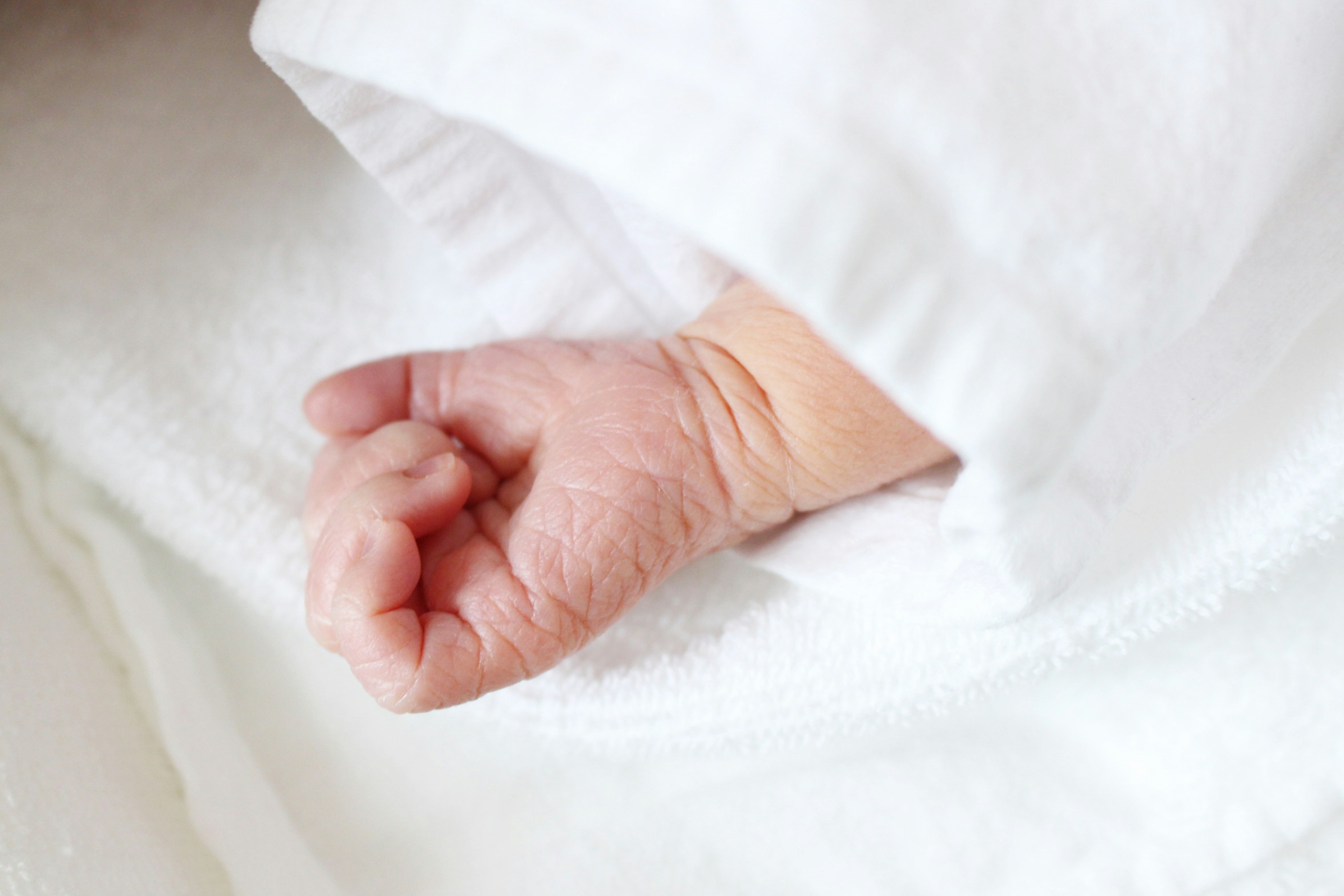 Baby hand peeking from white fabric