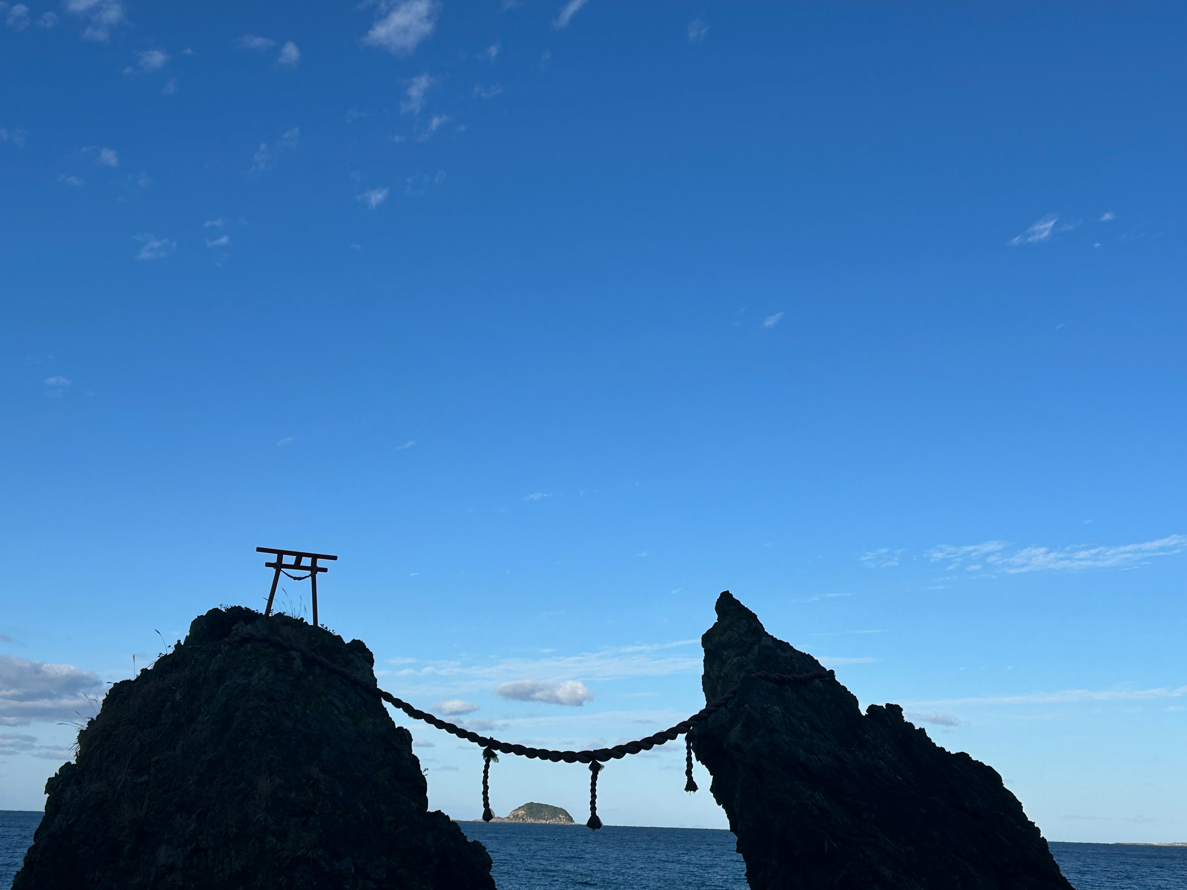 Eine Brücke und ein Torii zwischen Felsen unter einem blauen Himmel