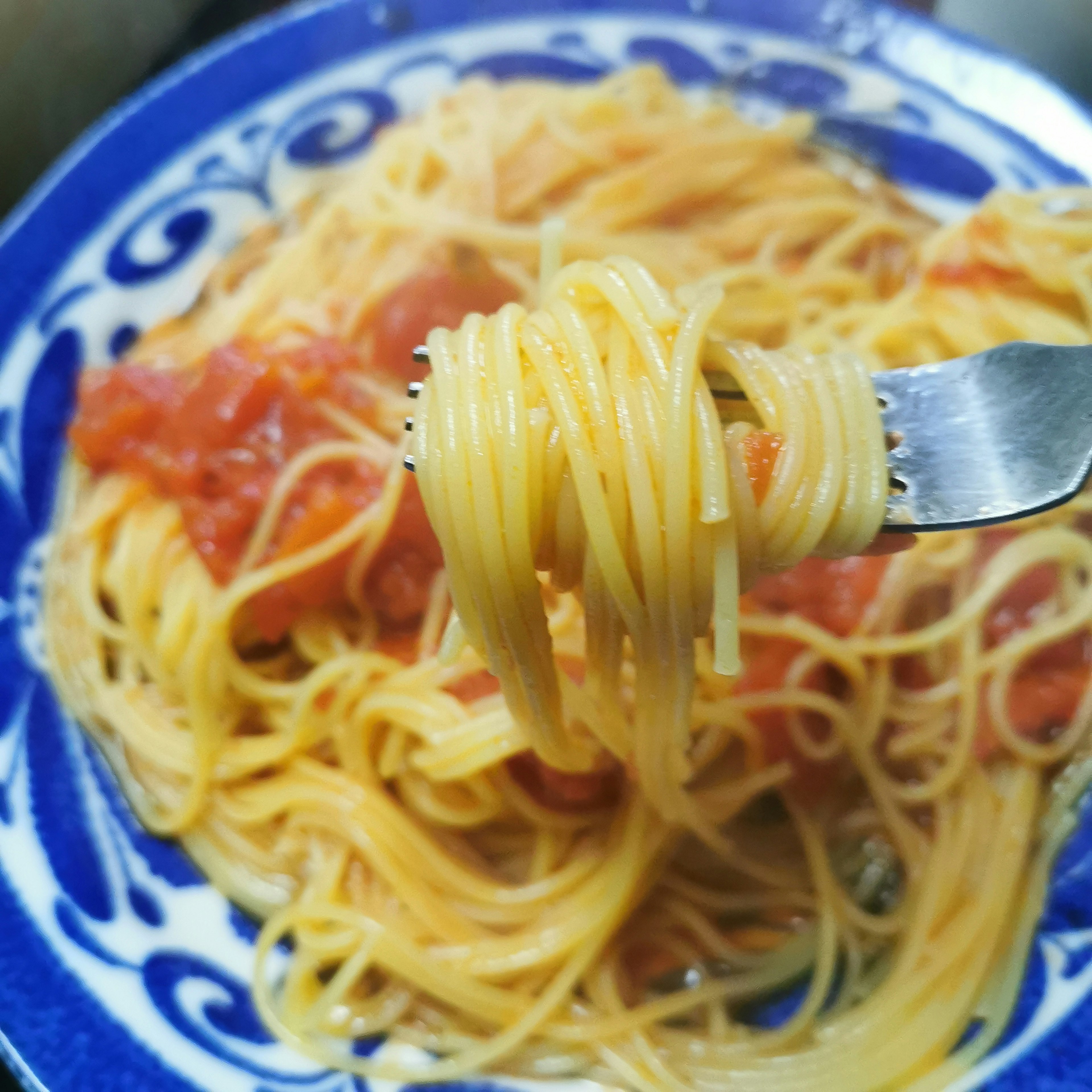 Spaghetti auf einer Gabel mit Tomatensauce auf einem dekorativen Teller