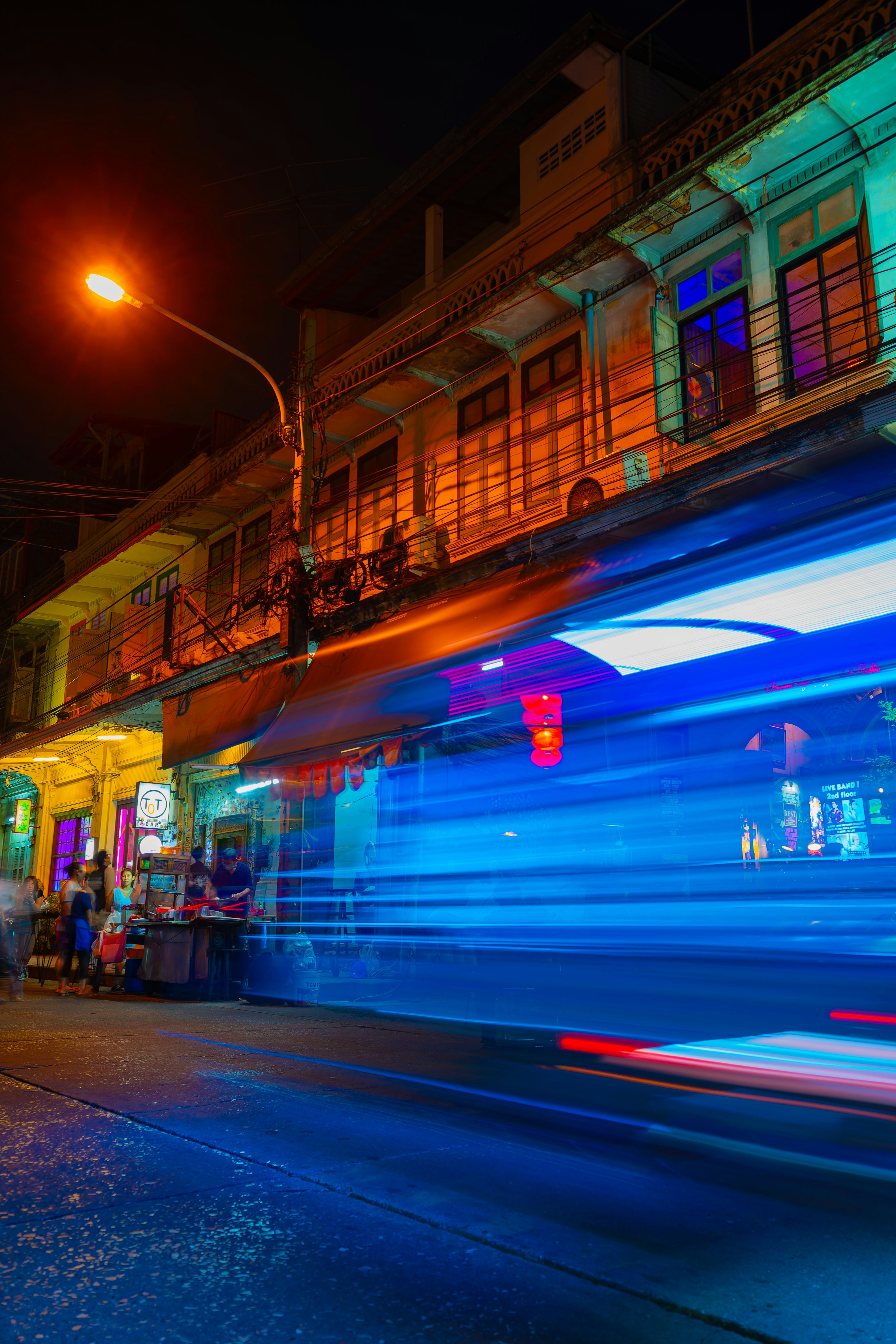 Nighttime street scene with colorful neon lights and blurred motion of passing vehicles