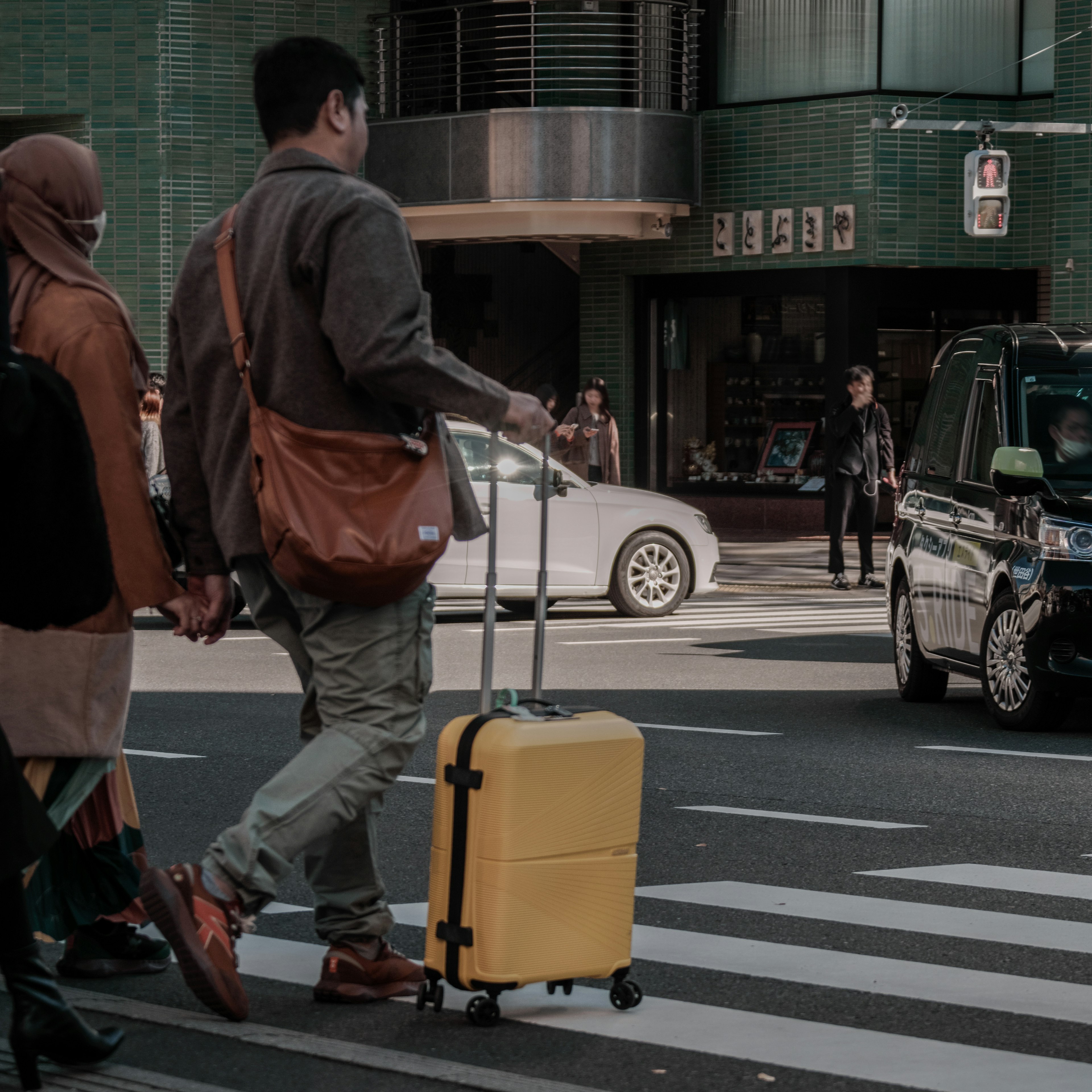 Uomo con valigia gialla che attraversa la strada