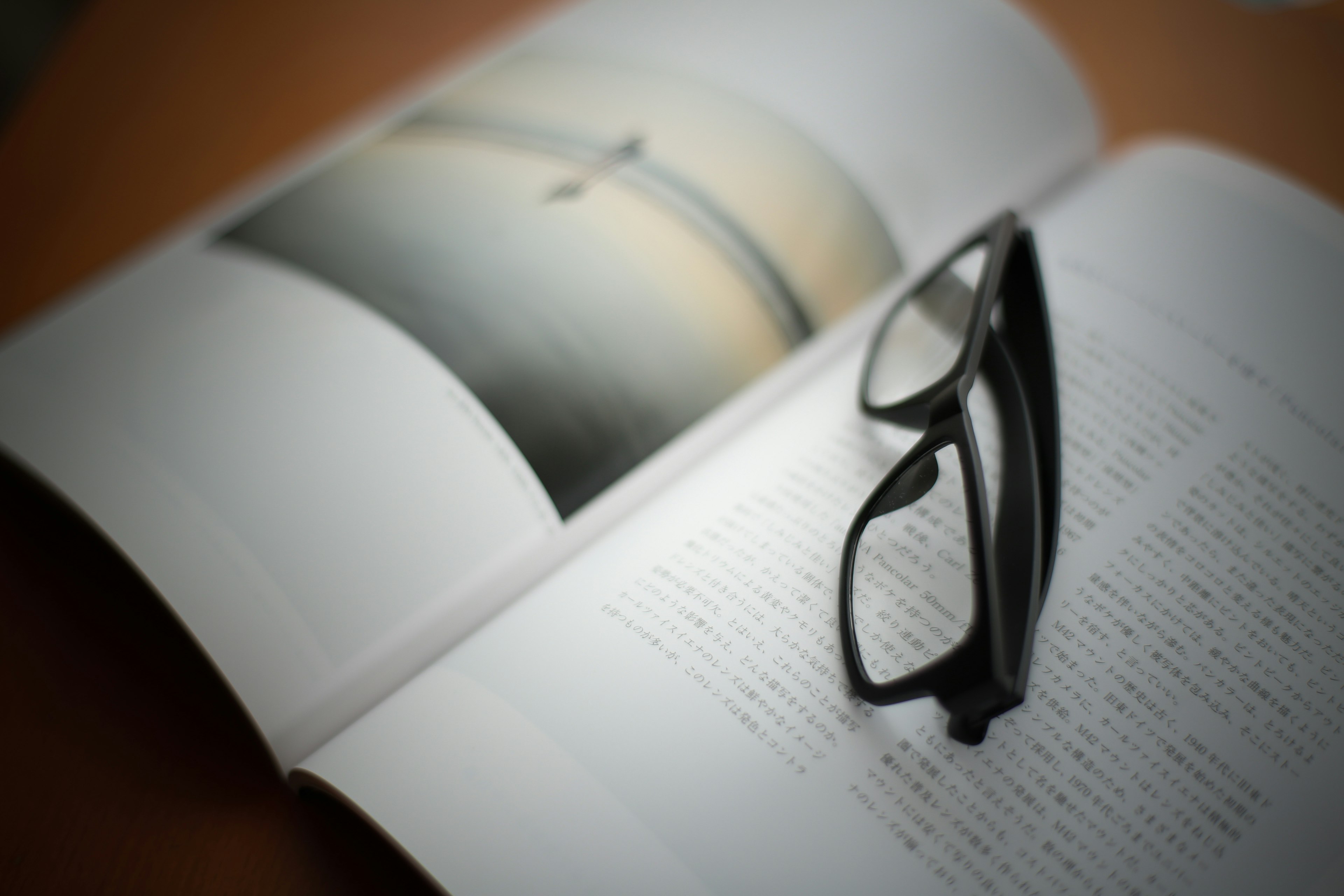 Black glasses resting on an open book with a photo page