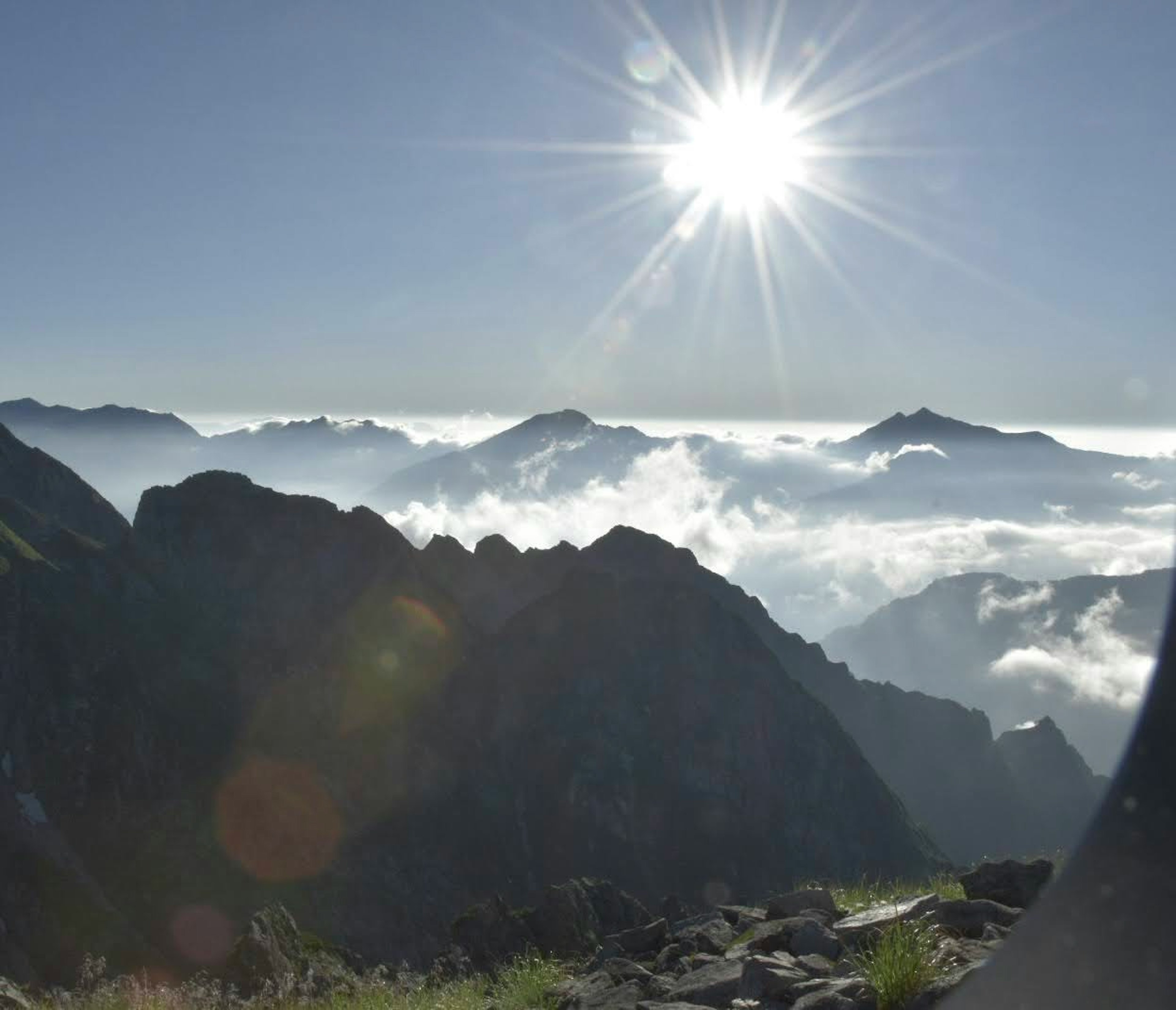 Montañas majestuosas con un mar de nubes y un sol brillante