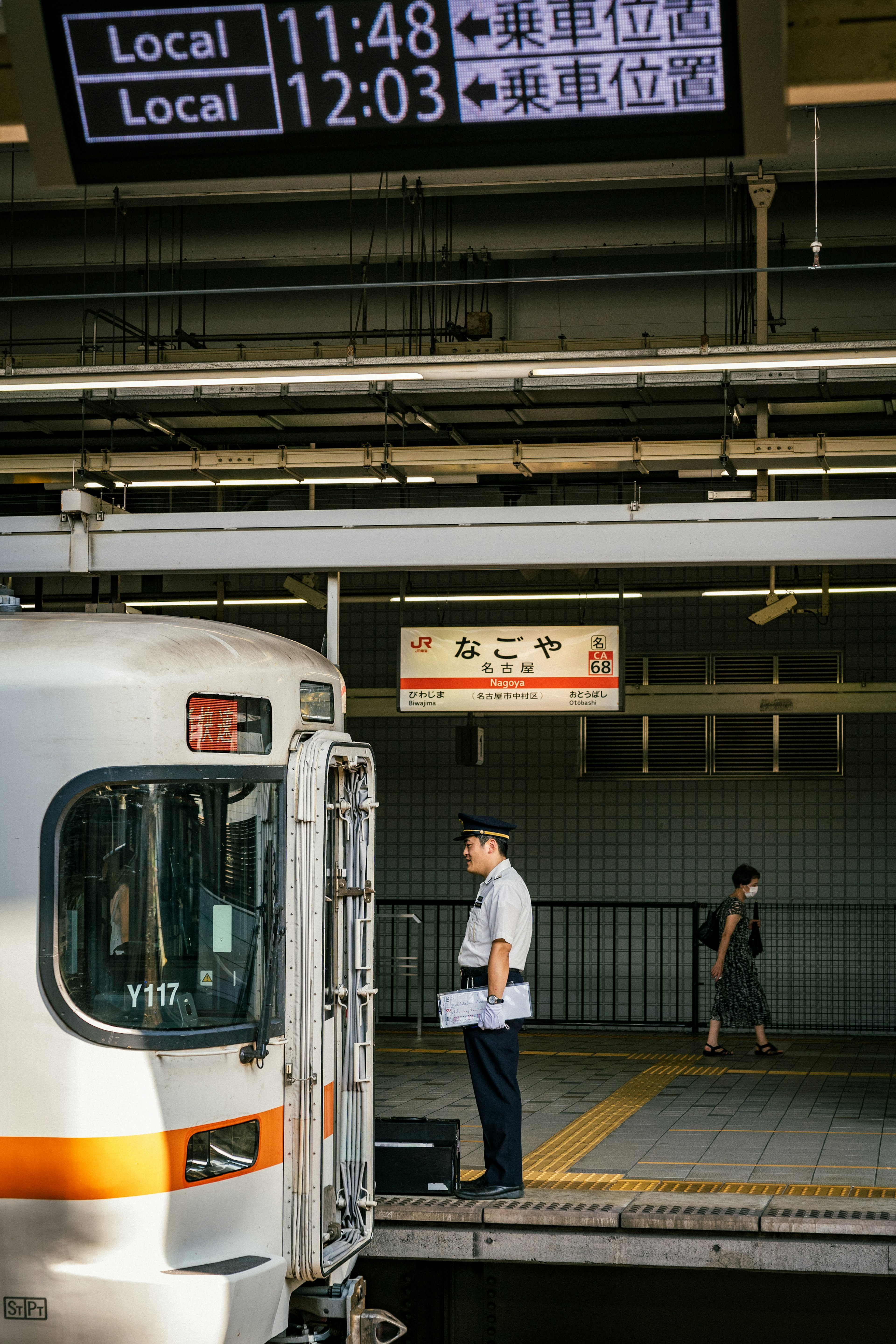 Conductor de tren de pie junto a un tren local en la plataforma