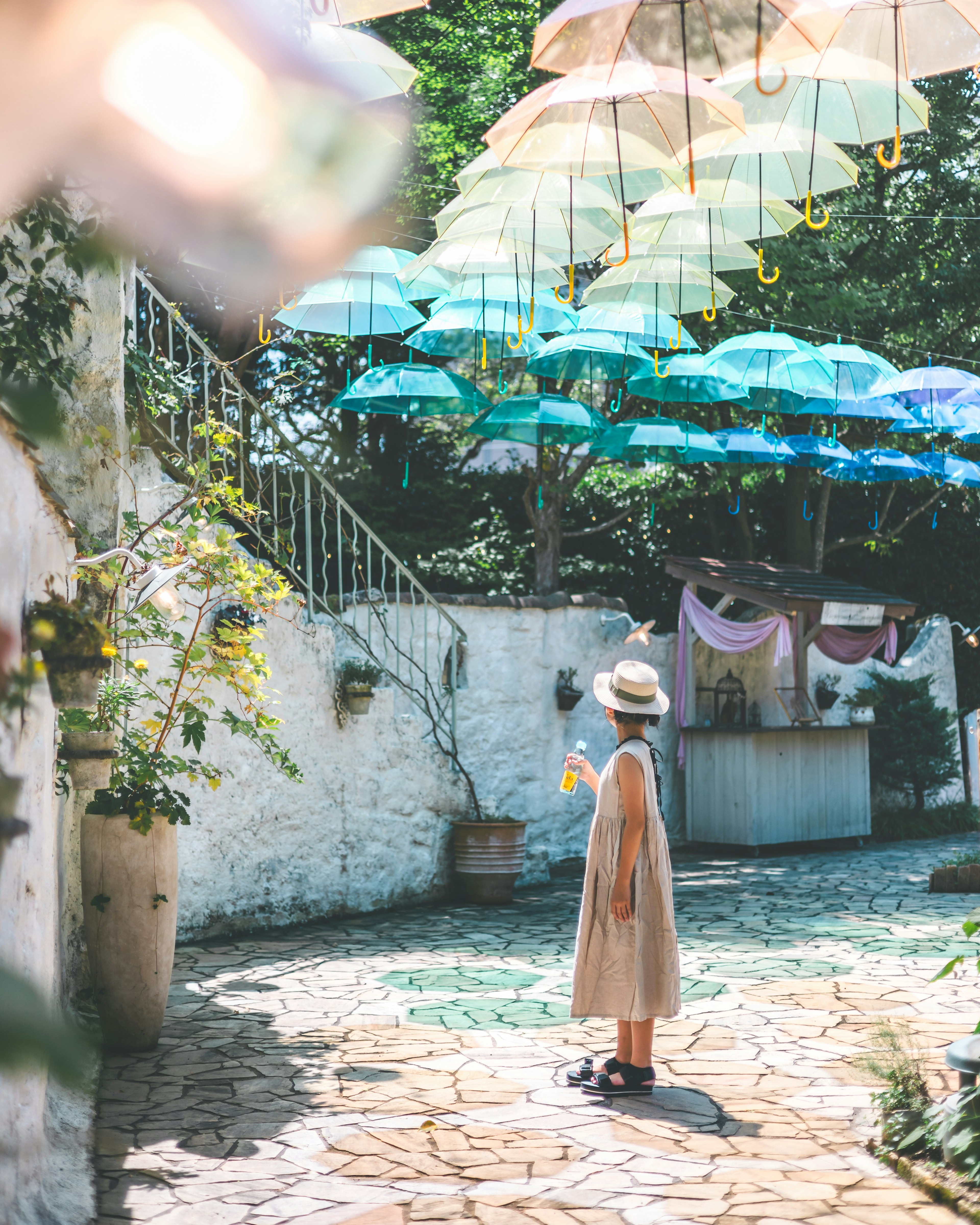 A woman standing in a colorful street adorned with hanging umbrellas