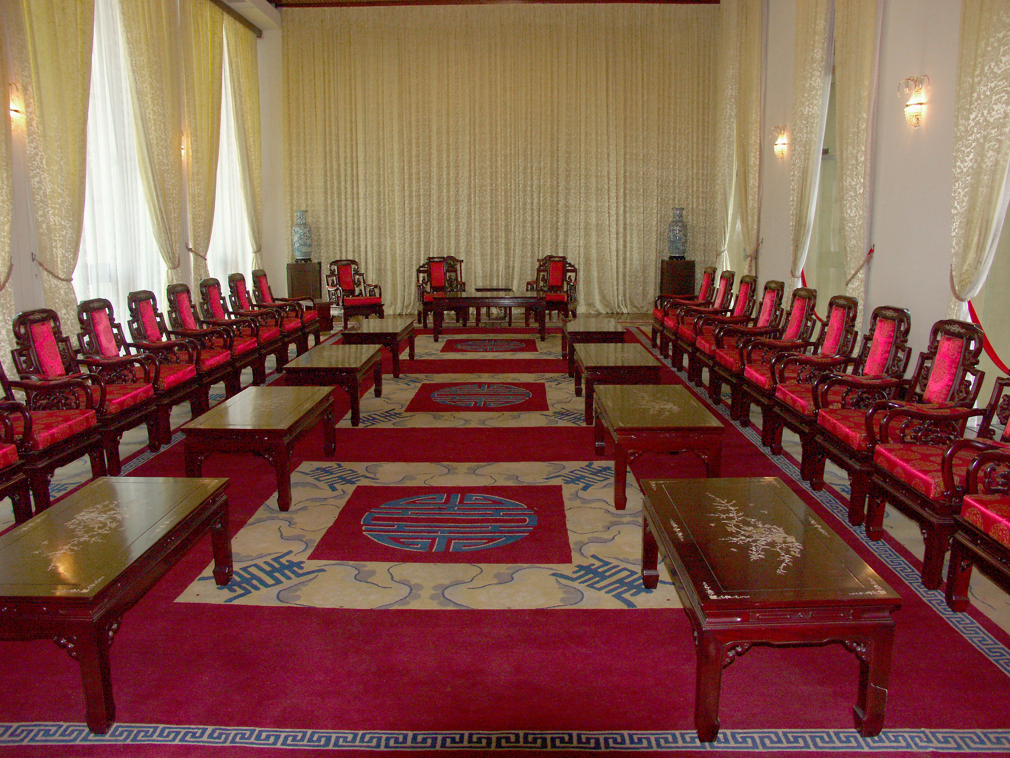 Interior of a lavish room with red chairs and tables arranged neatly