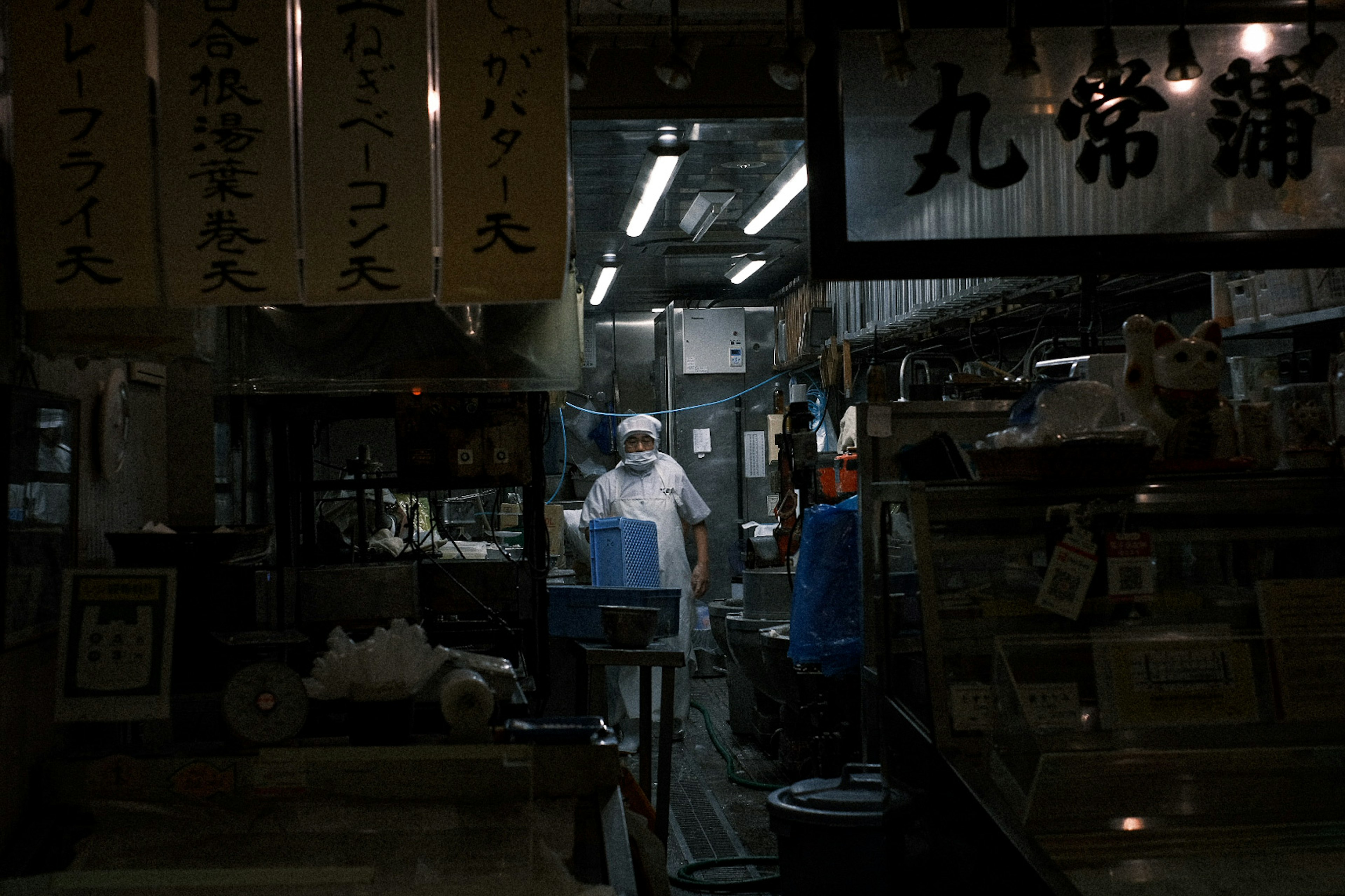 Escena de personas trabajando en un mercado nocturno con letreros japoneses