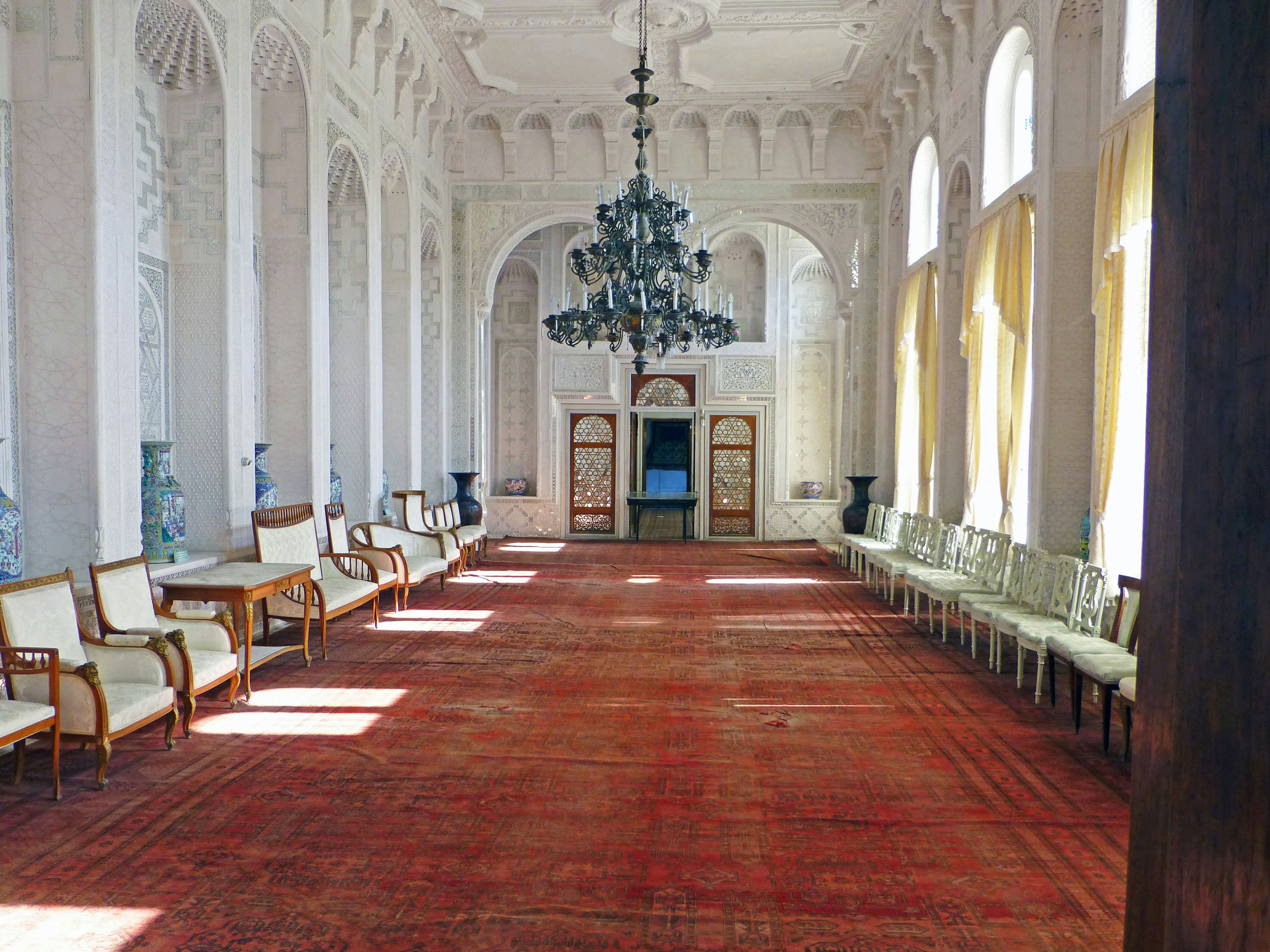 Spacious room featuring an elegant chandelier and a long carpet