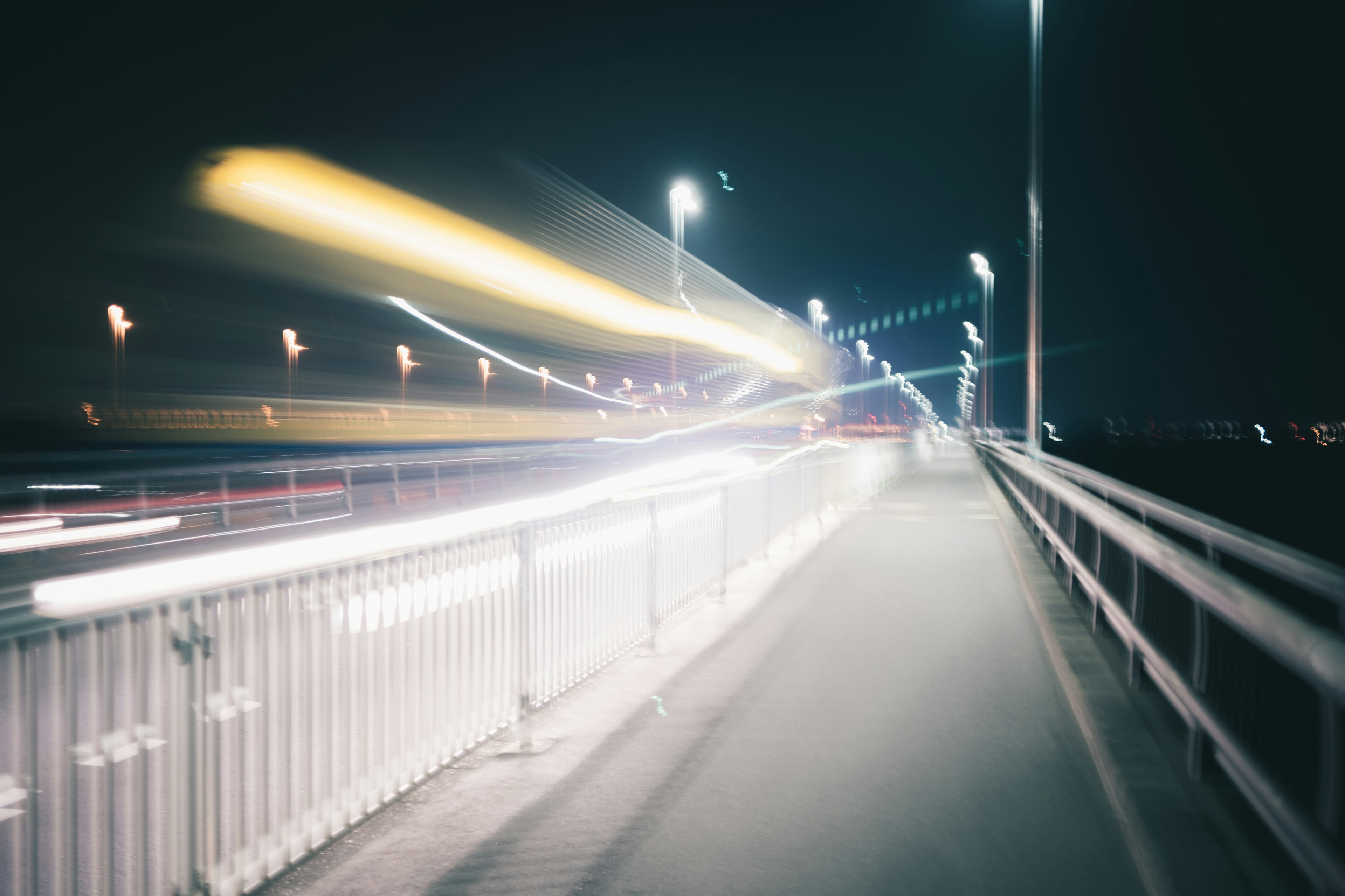 Scena notturna di un ponte con scie di luce e lampioni