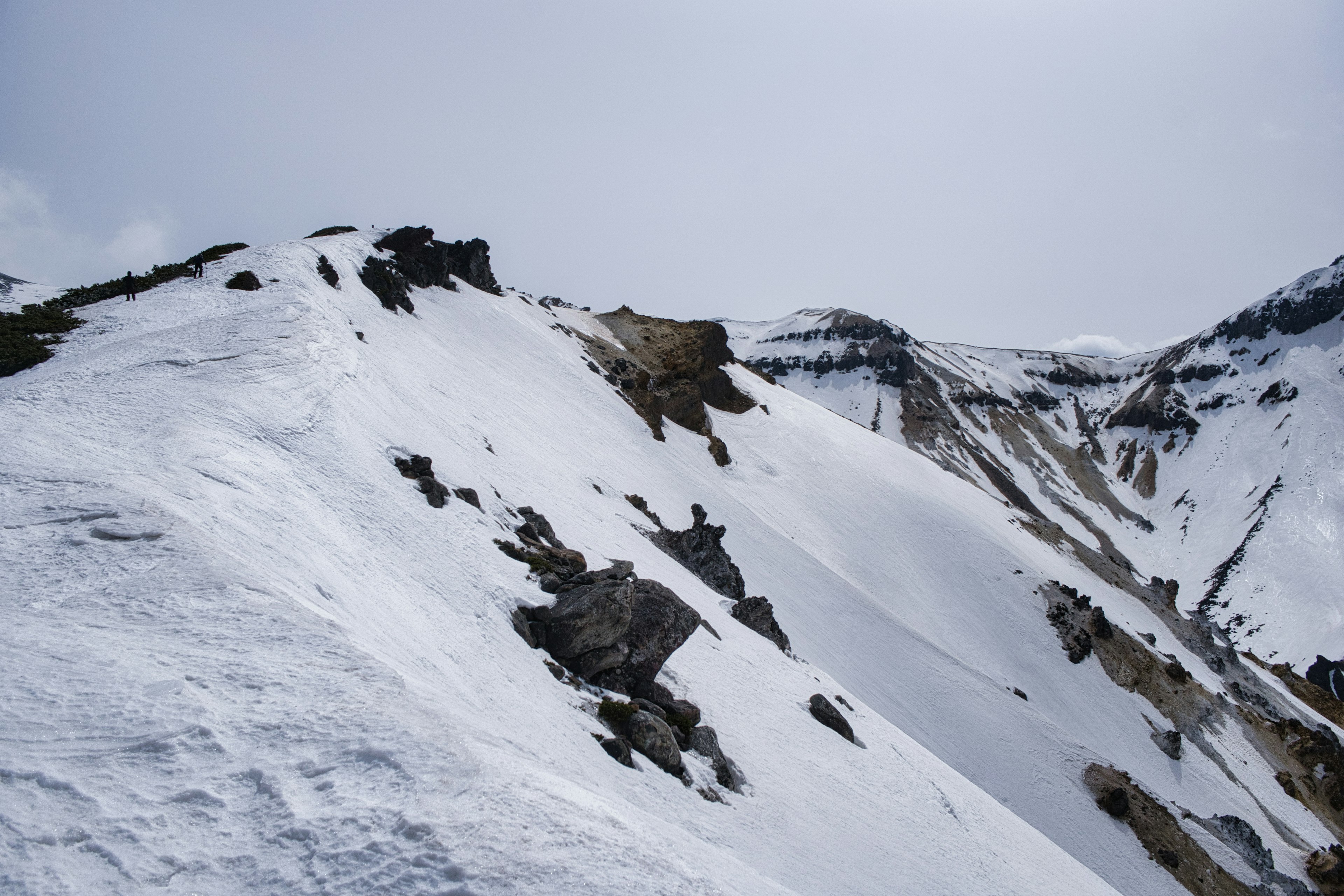 Snow-covered mountain slope with exposed rocks and rugged terrain