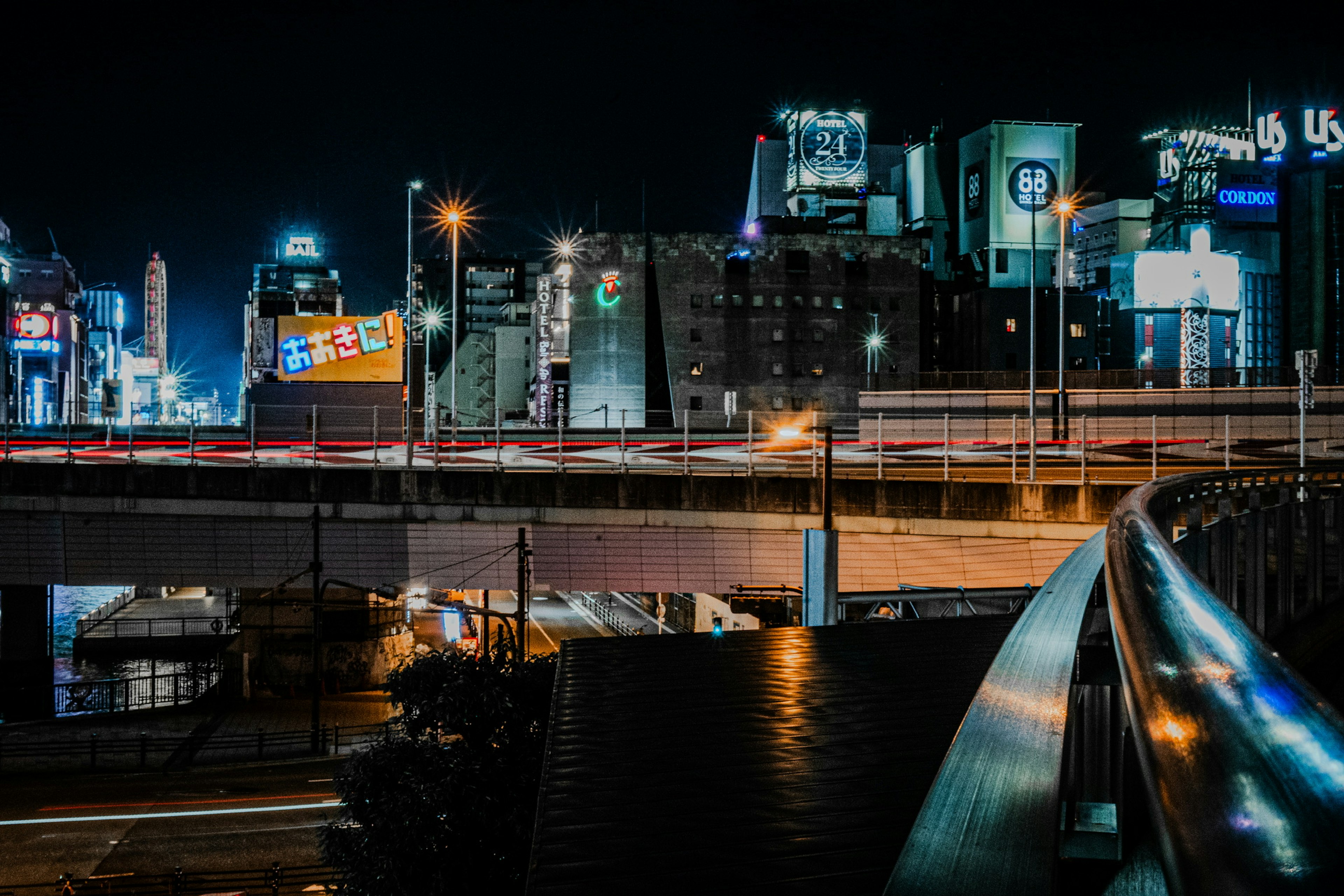 Paysage urbain nocturne avec autoroute et bâtiments illuminés par des enseignes au néon