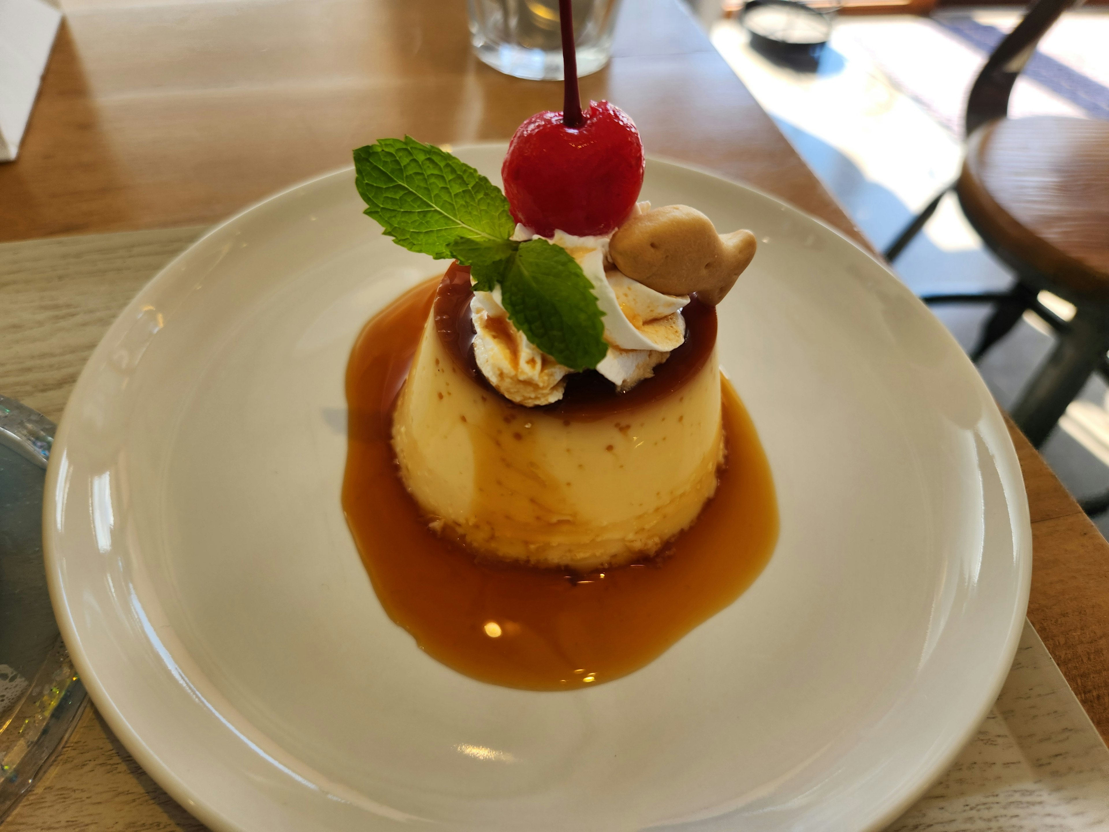 Postre flan decorado con salsa de caramelo crema batida cereza y menta