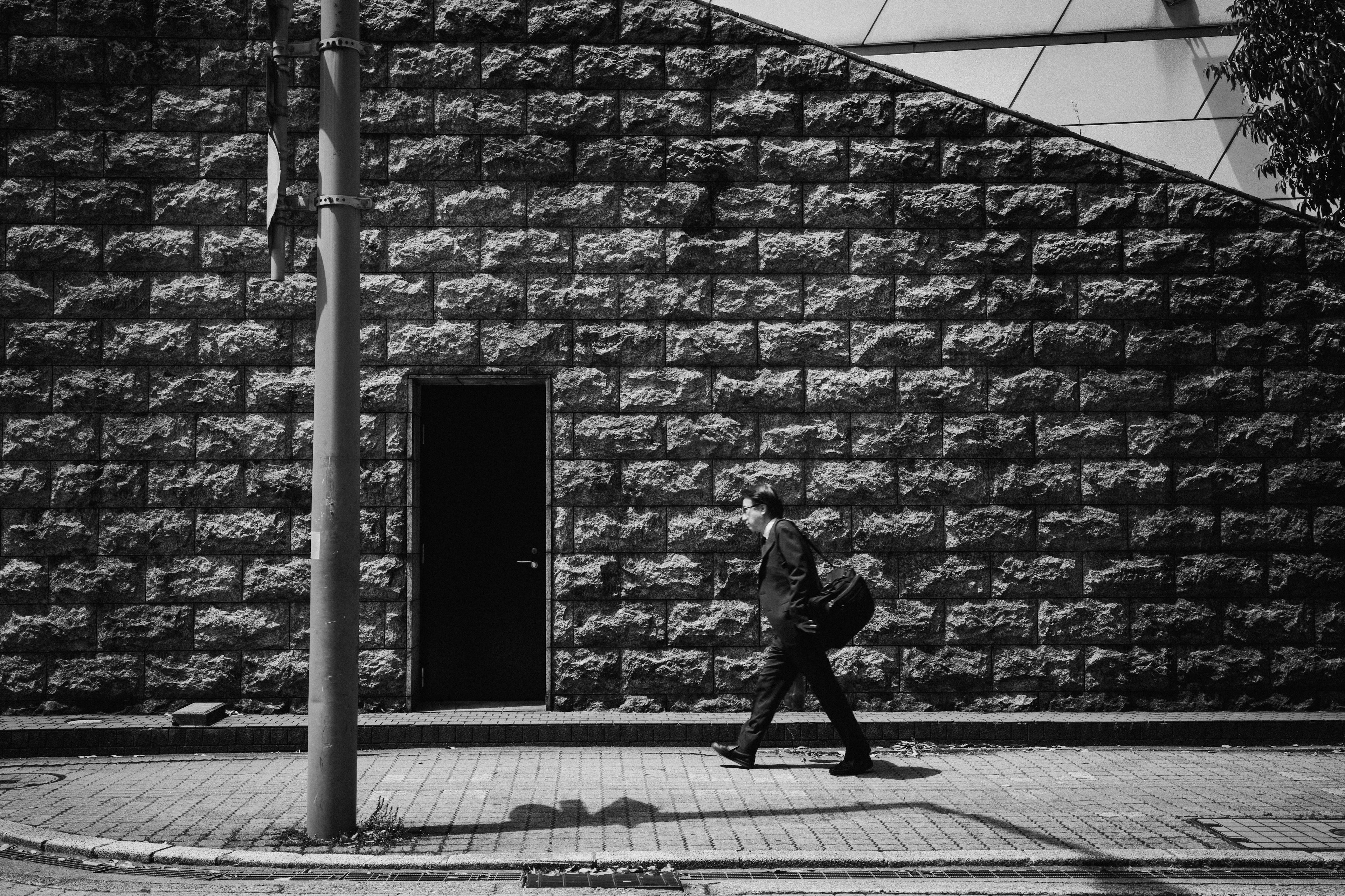 Persona caminando frente a una pared de piedra negra y una puerta