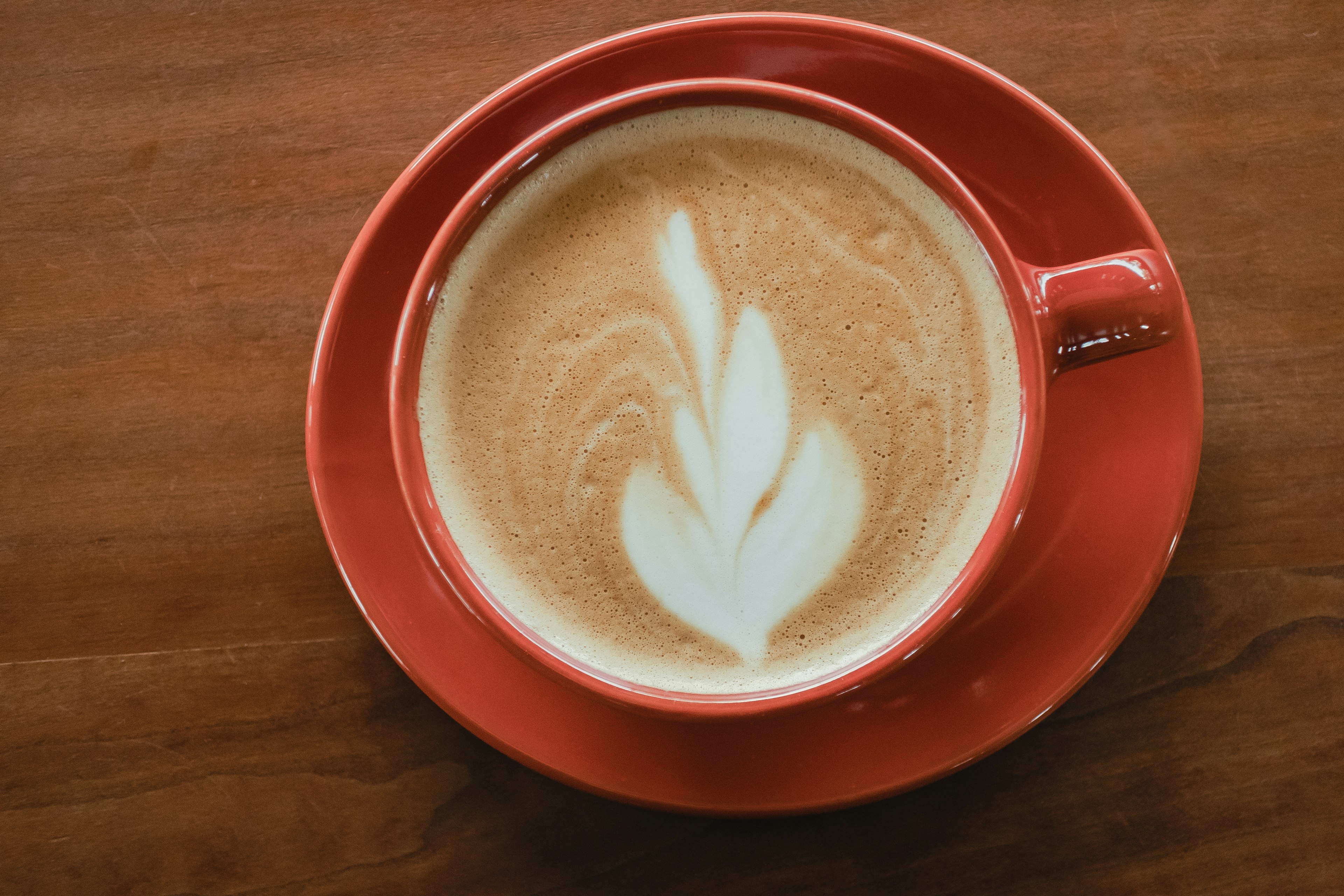 Kopi latte dengan seni latte dalam cangkir merah