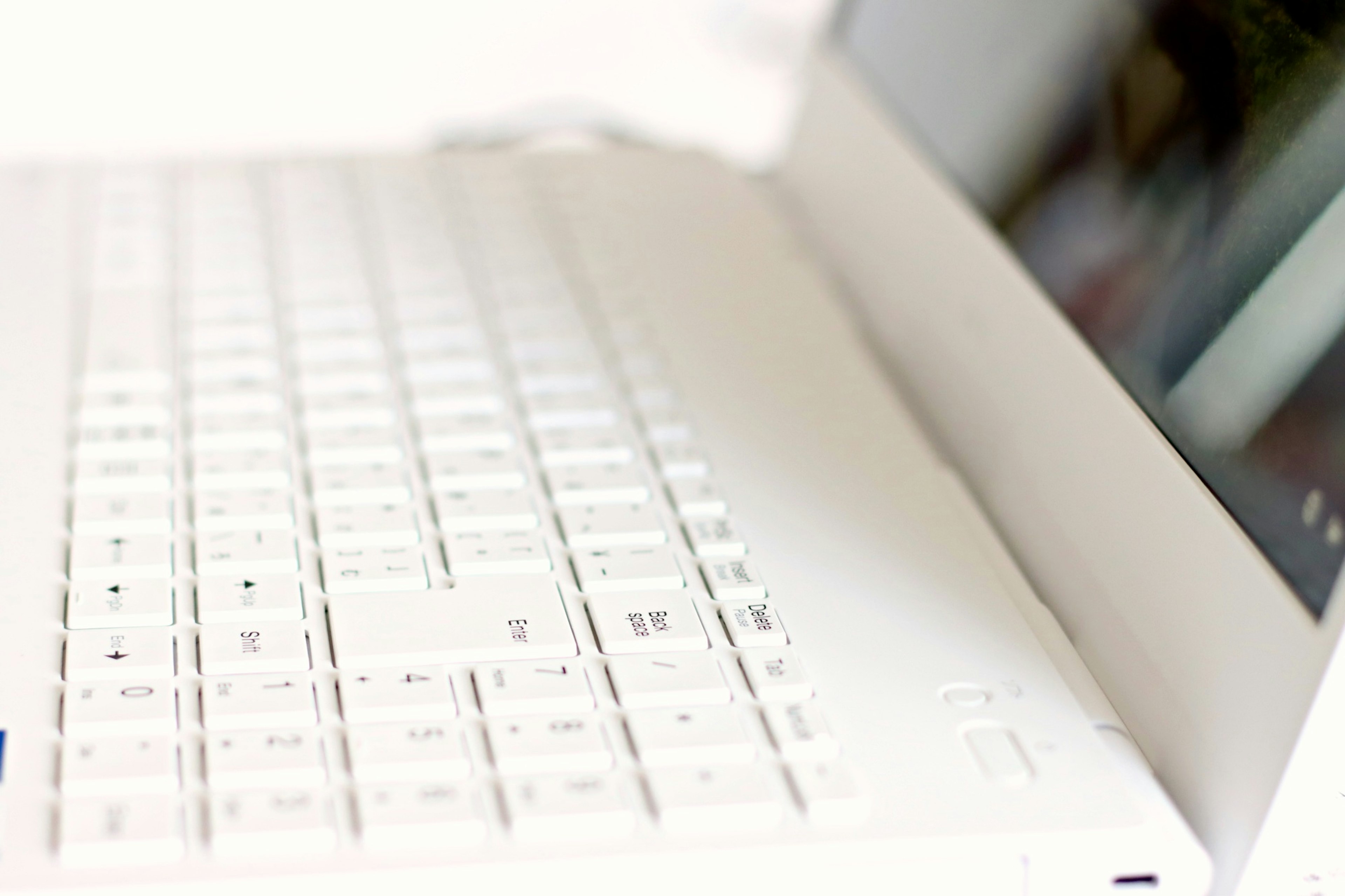 Imagen que muestra un teclado blanco y la vista lateral de una laptop delgada