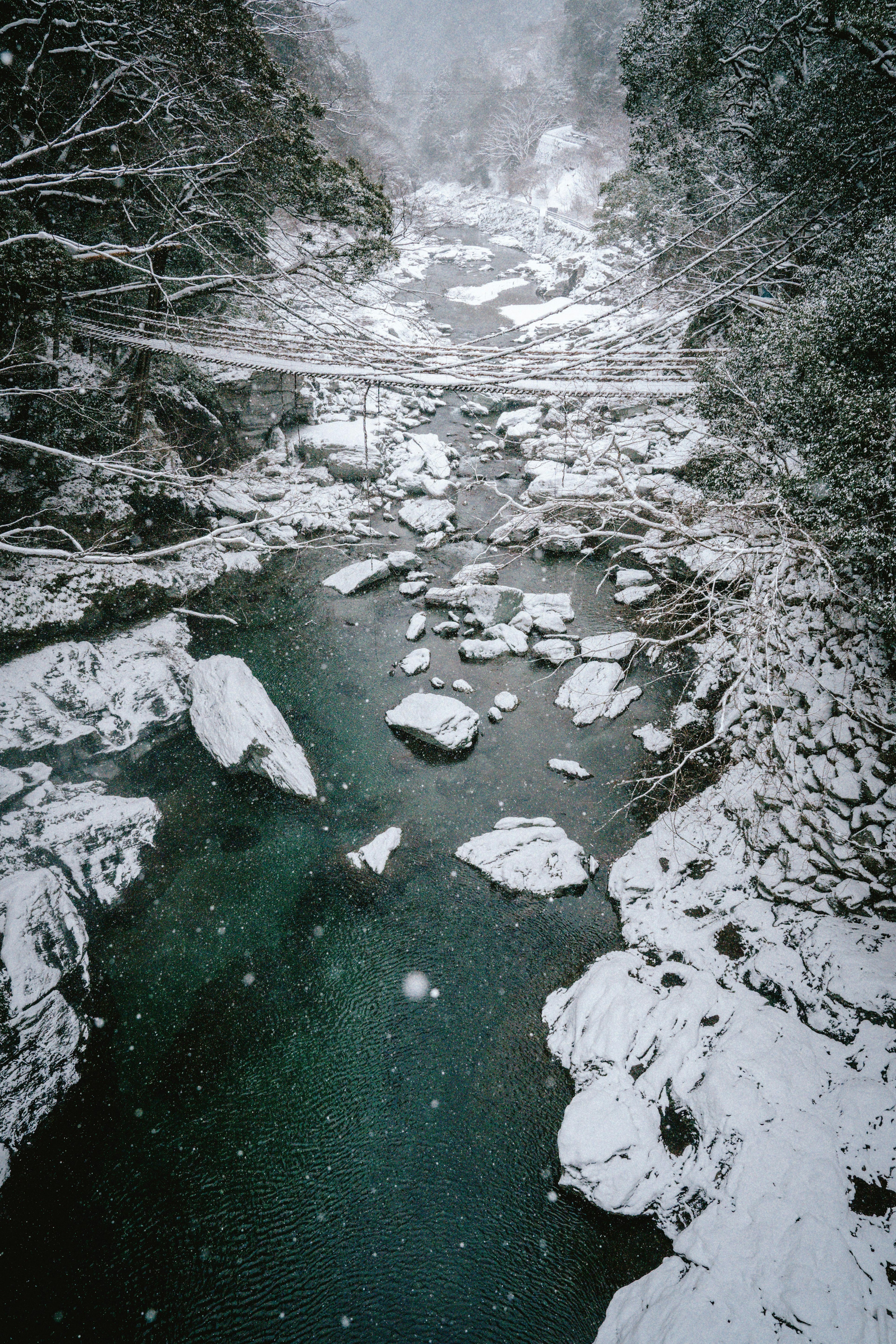 Paesaggio invernale con un fiume innevato e rocce