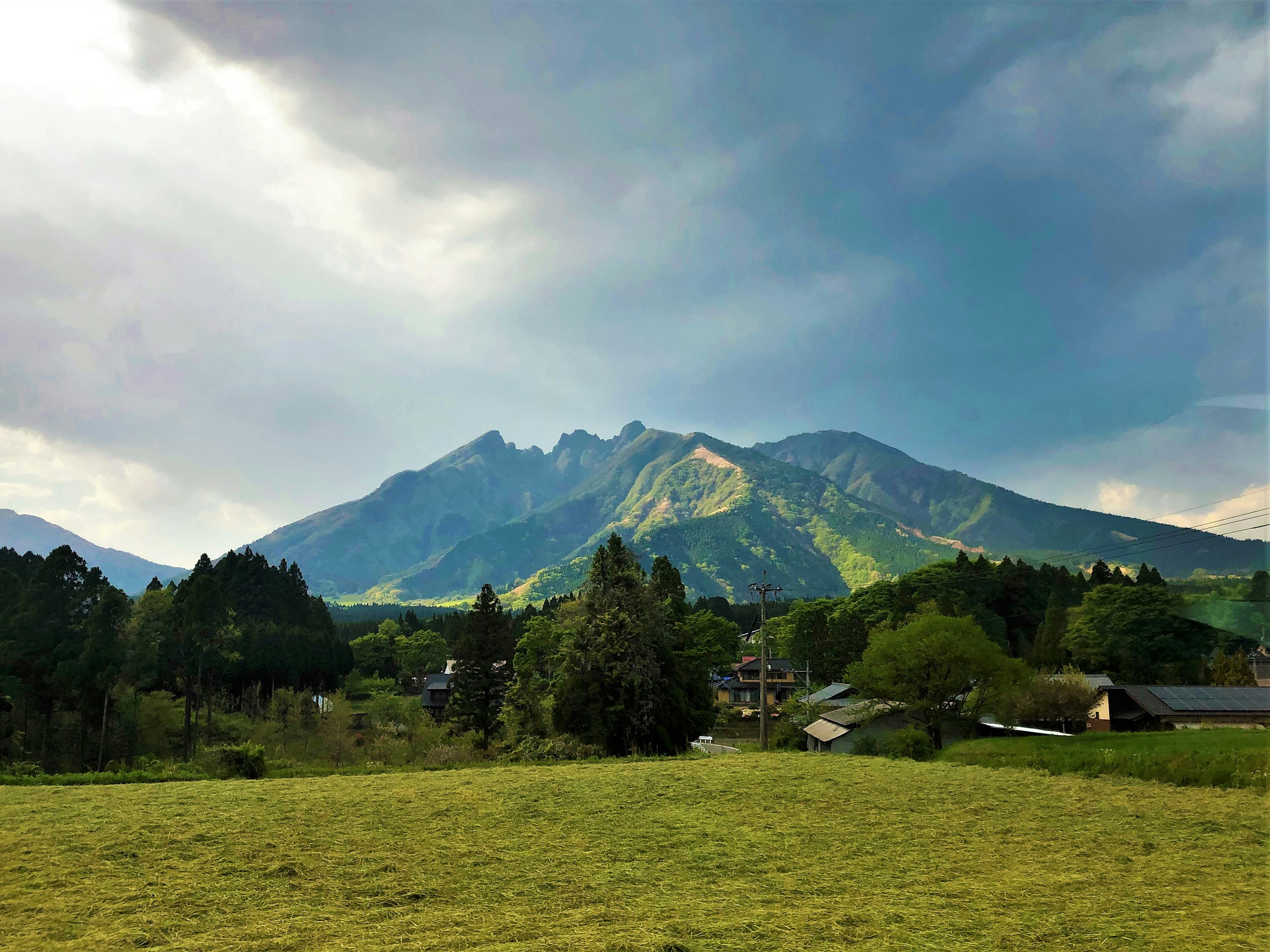 Eine Landschaft mit einer grünen Bergkette unter einem bewölkten Himmel