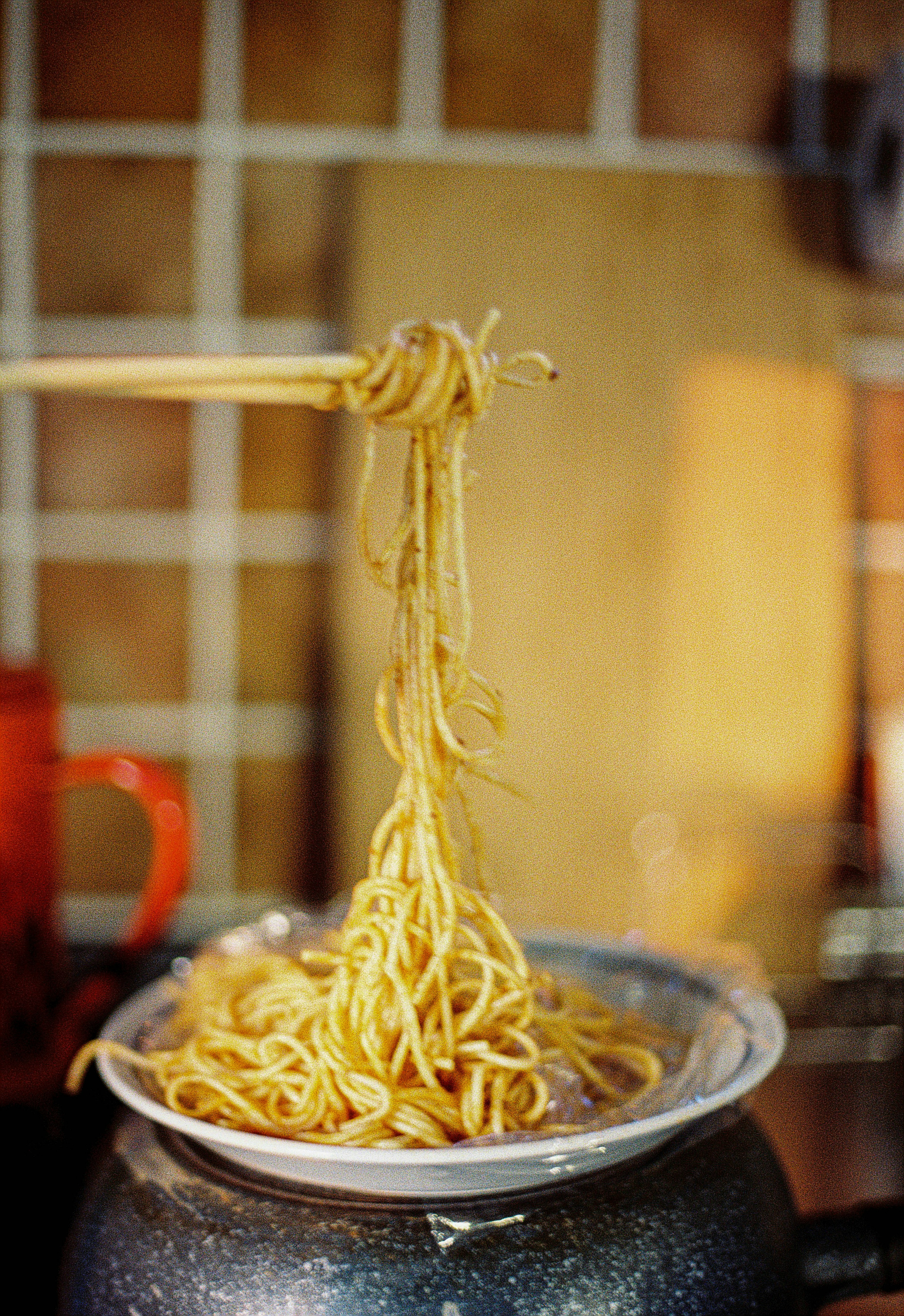 Bacchette che sollevano spaghetti sottili da una ciotola